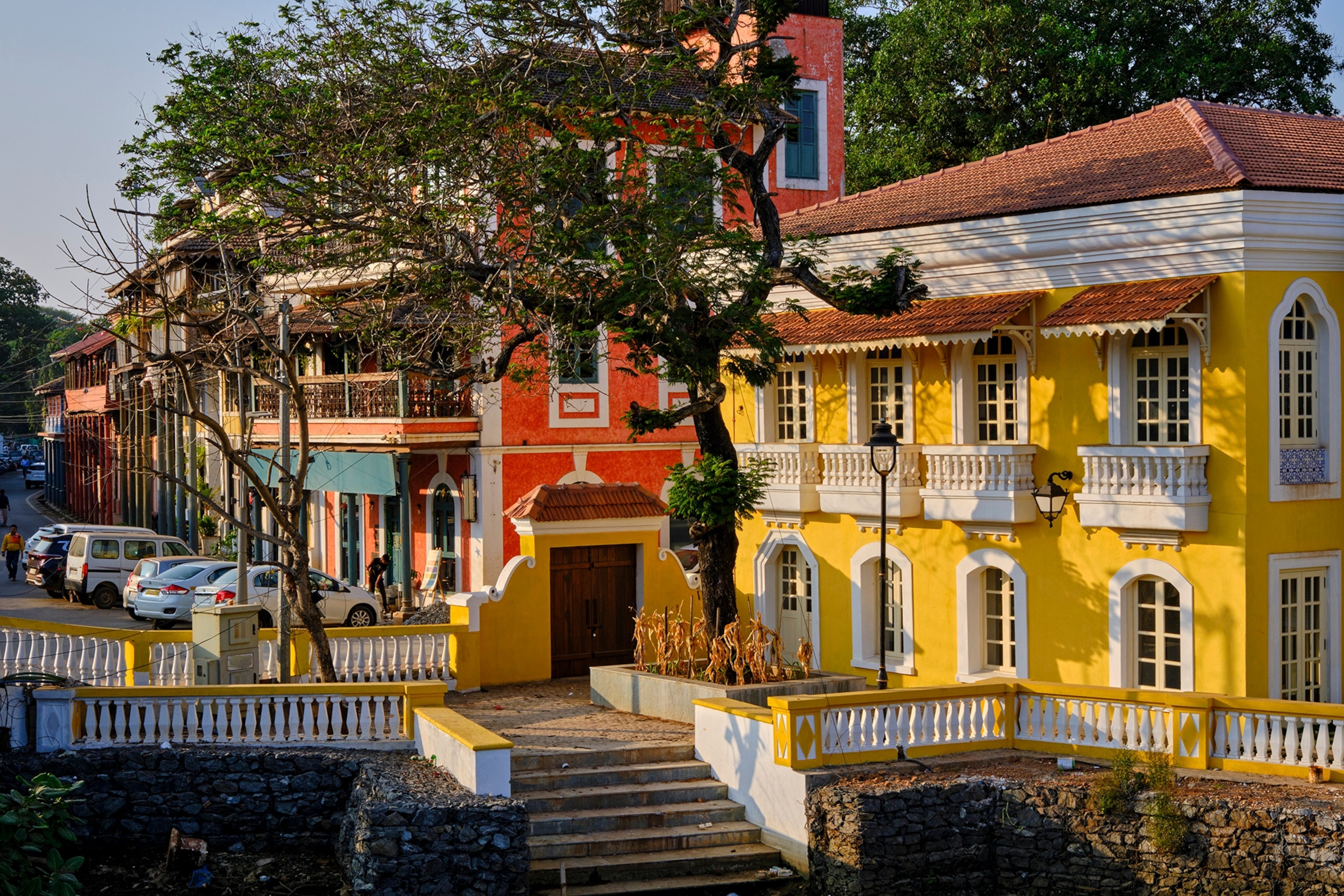 A colourful, colonial-style town with small balconies and stone step leading down a pathway.