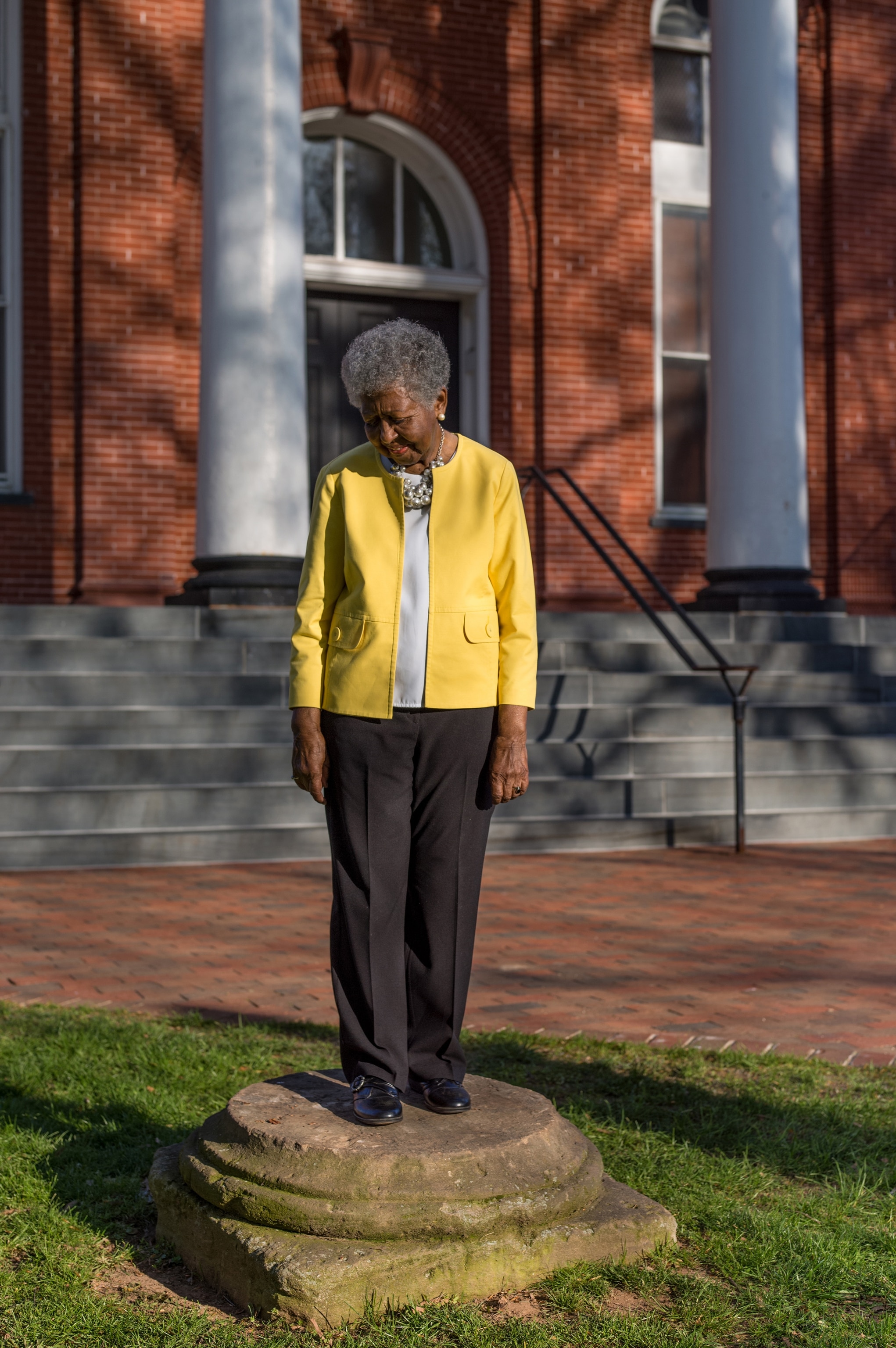 Elaine E. Thompson standing on an old courthouse pillar