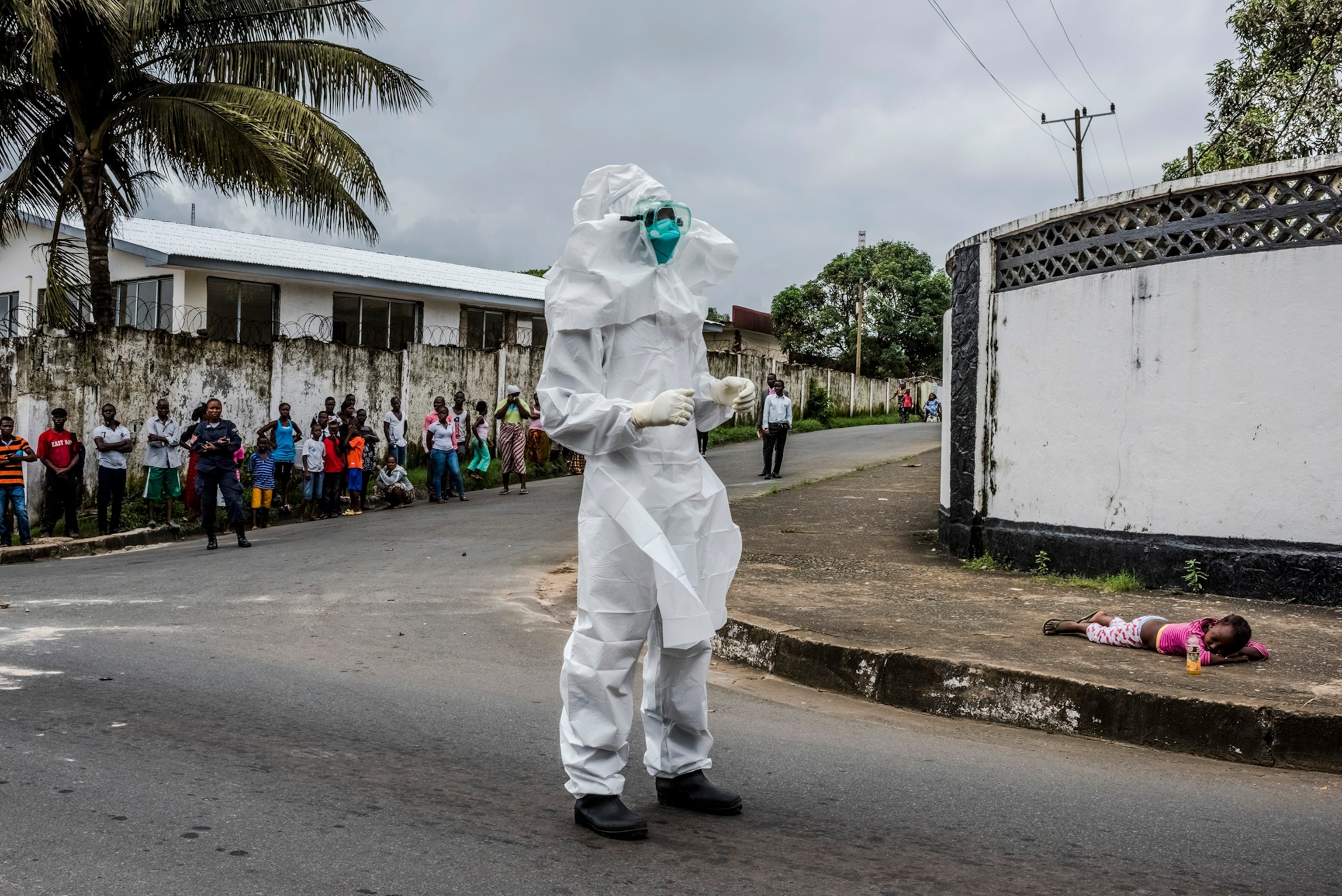 A girl suspected of having Ebola lies on a sidewalk, where her aunt left her after she was unable to get help, in Monrovia, Liberia, Aug. 31, 2014. Liberia remains desperately short on everything needed to halt the spread of Ebola, but an epidemiologist is working block by block to fill a crucial need: the support of residents. (Daniel Berehulak/The New York Times)