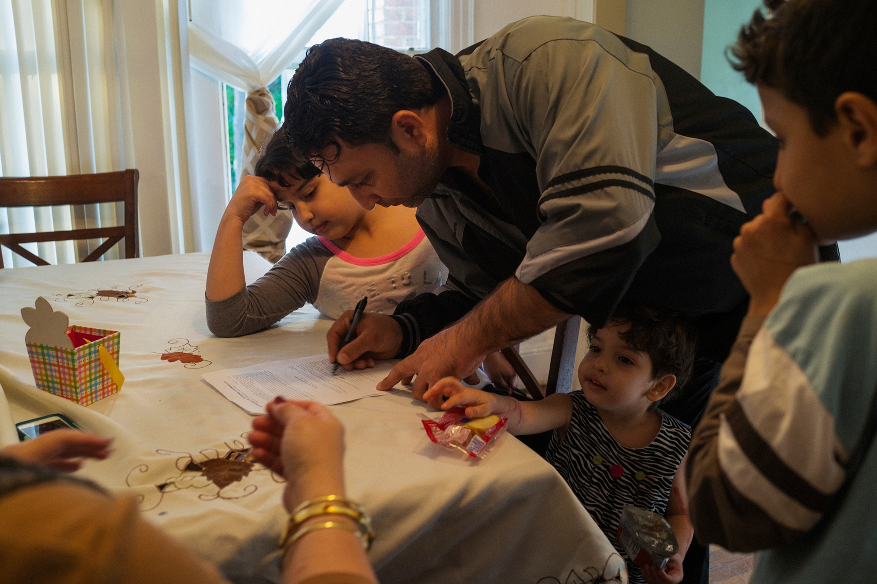 a man filling out paperwork while surrounded by three children