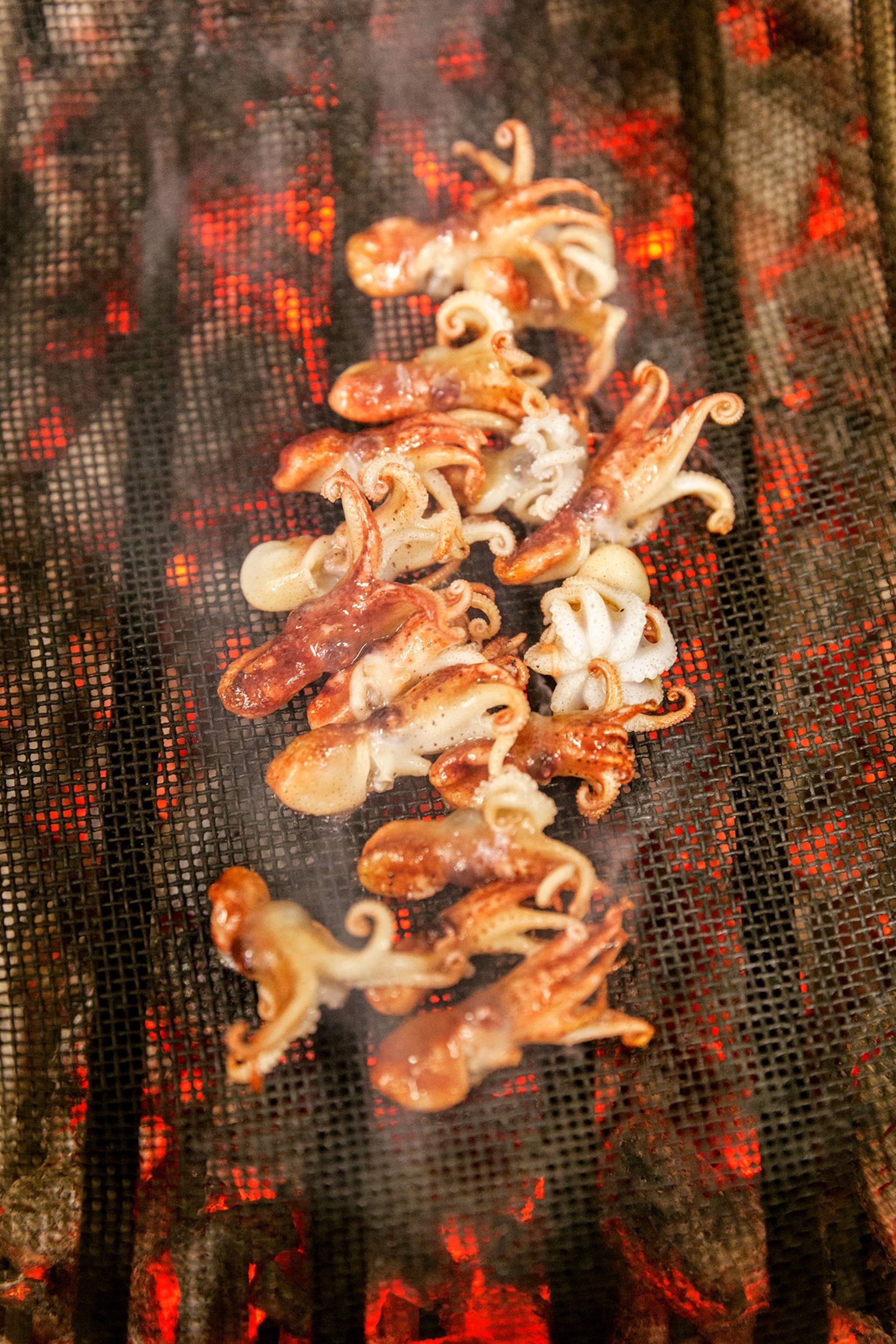 A collection of baby squid on a grill.