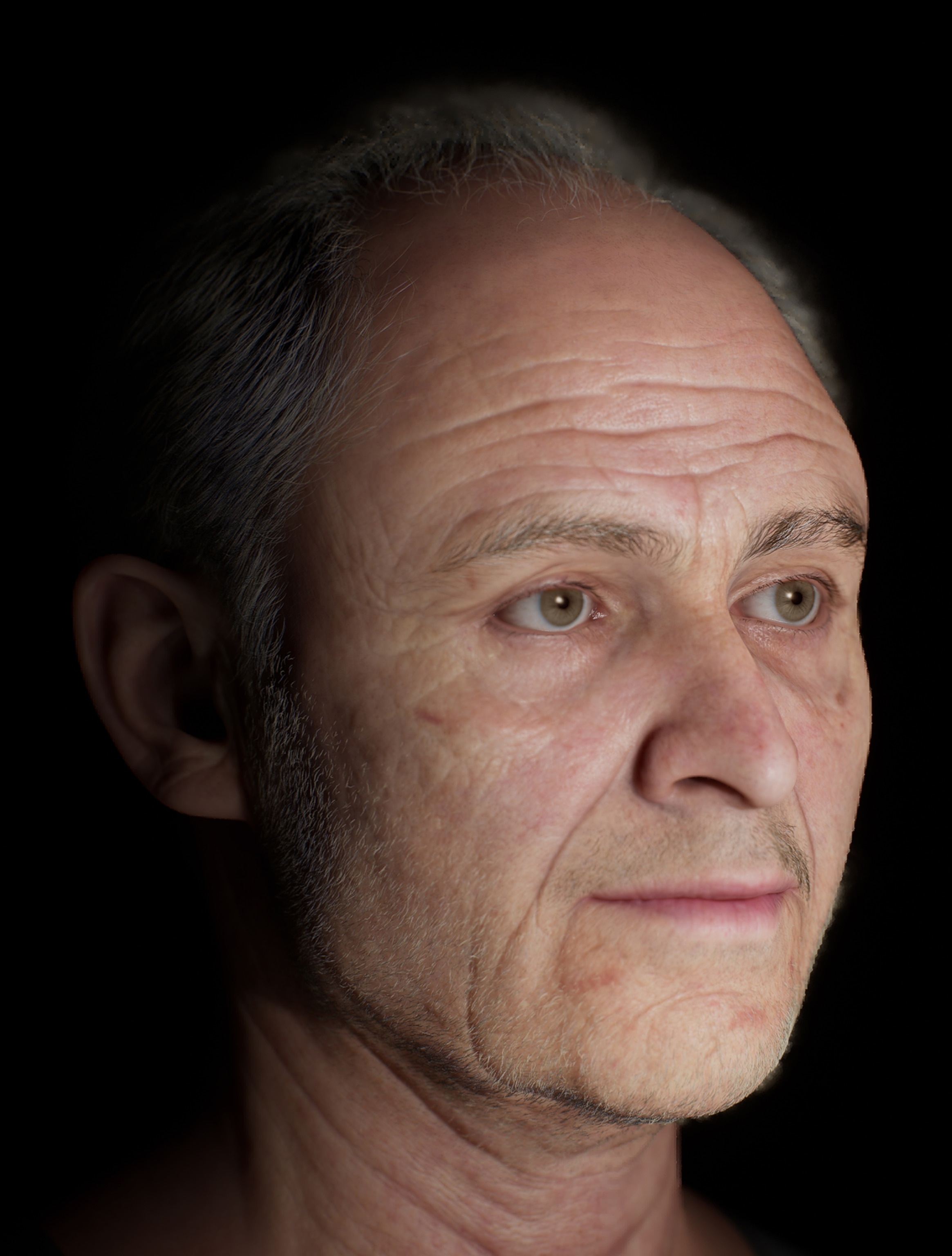An angled close up of an aging man with short gray hair and stubble.