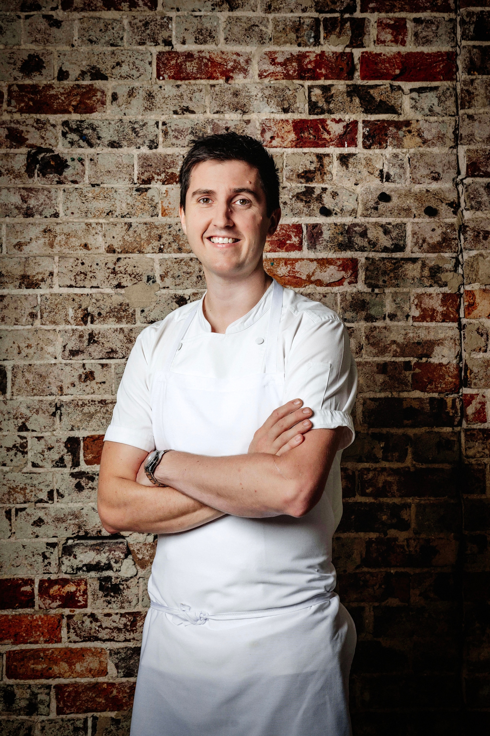 Chef Josh Niland in front of a brick wall