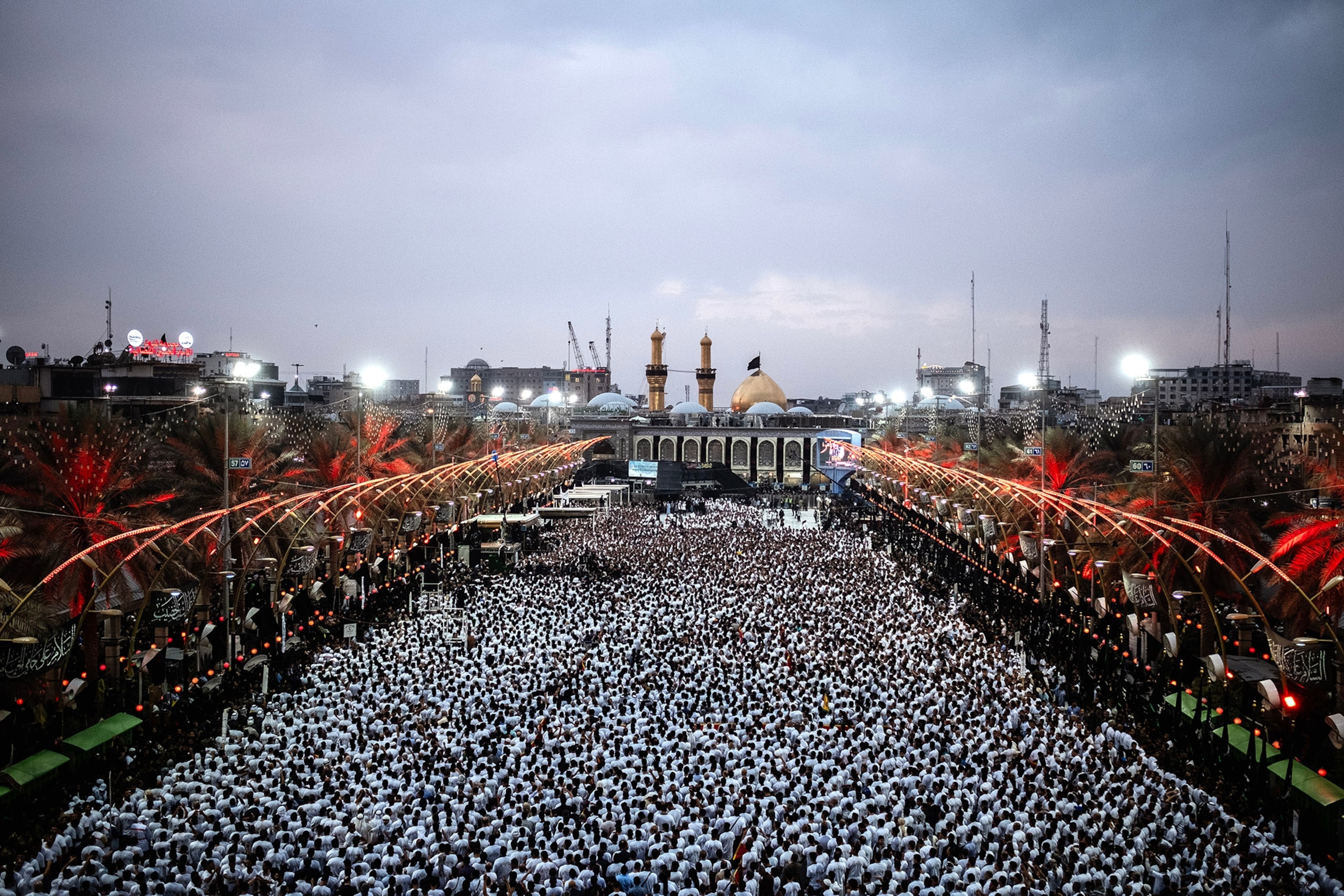 A crowd of people wearing white gather in front of a mosque