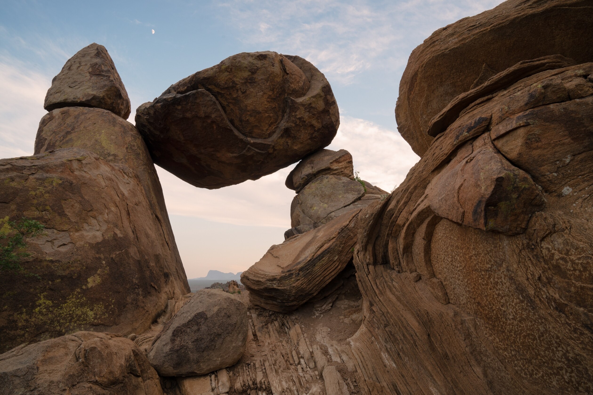 A large boulder balances between two rock stocks.