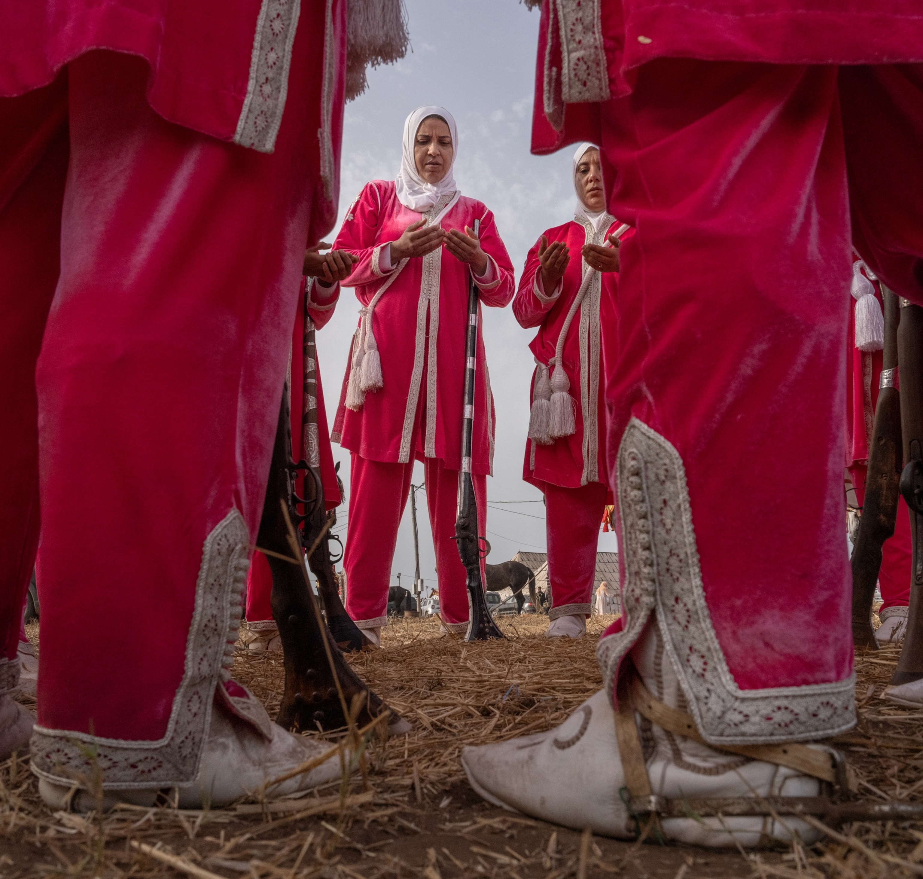 A group of women wearing pink and white stand in a circle all facing on another.