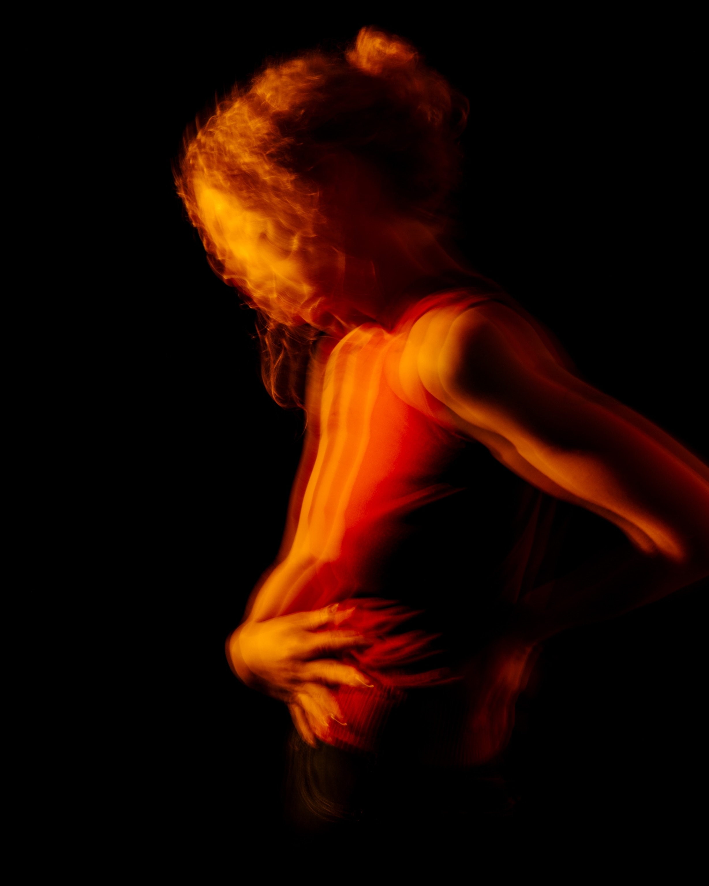 A blurry photo of a woman clutching her abdomen and lower back in pain