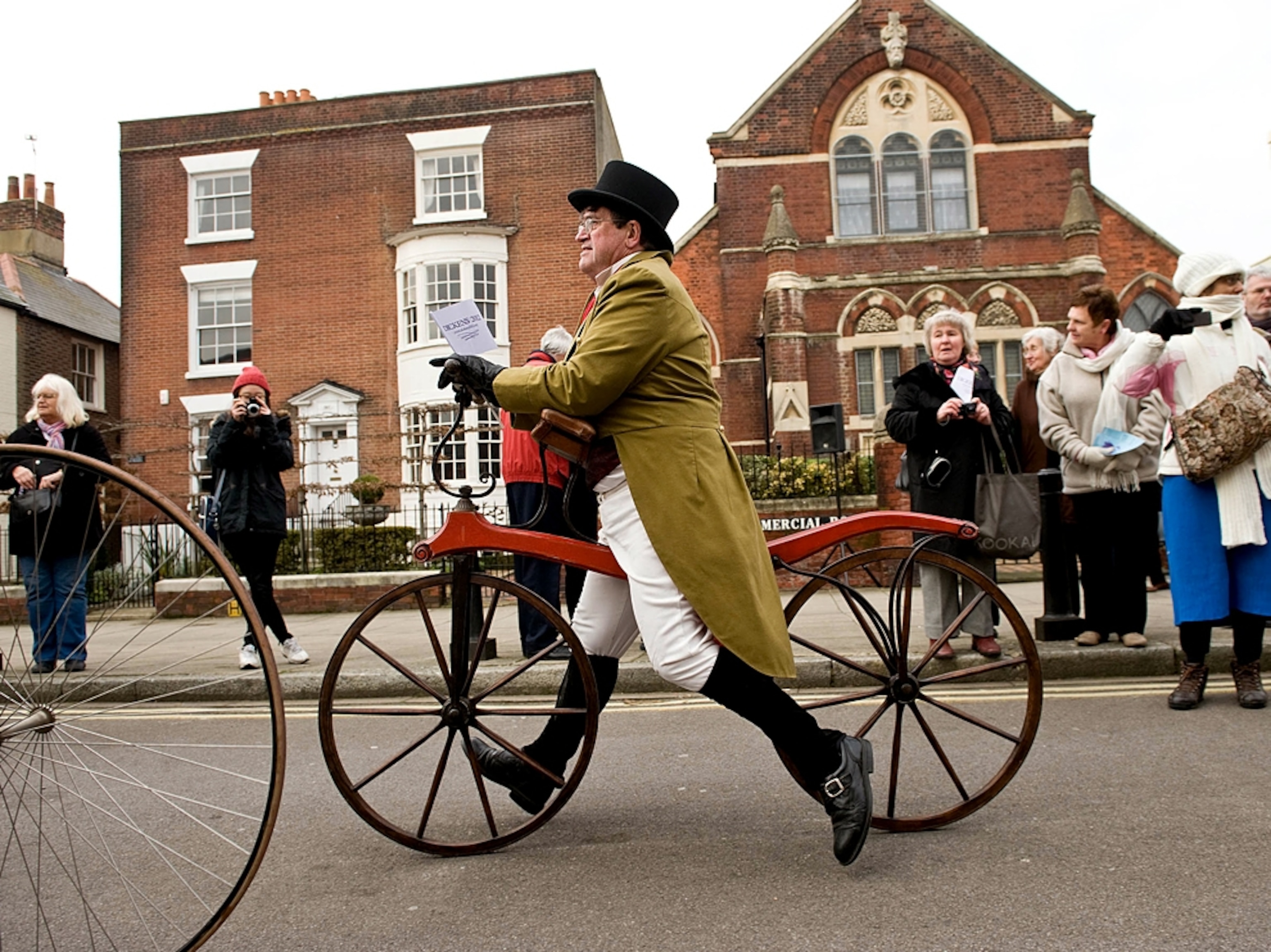 a man in period costume riding a bike during the Charles Dickens 200th birthday celebration, England