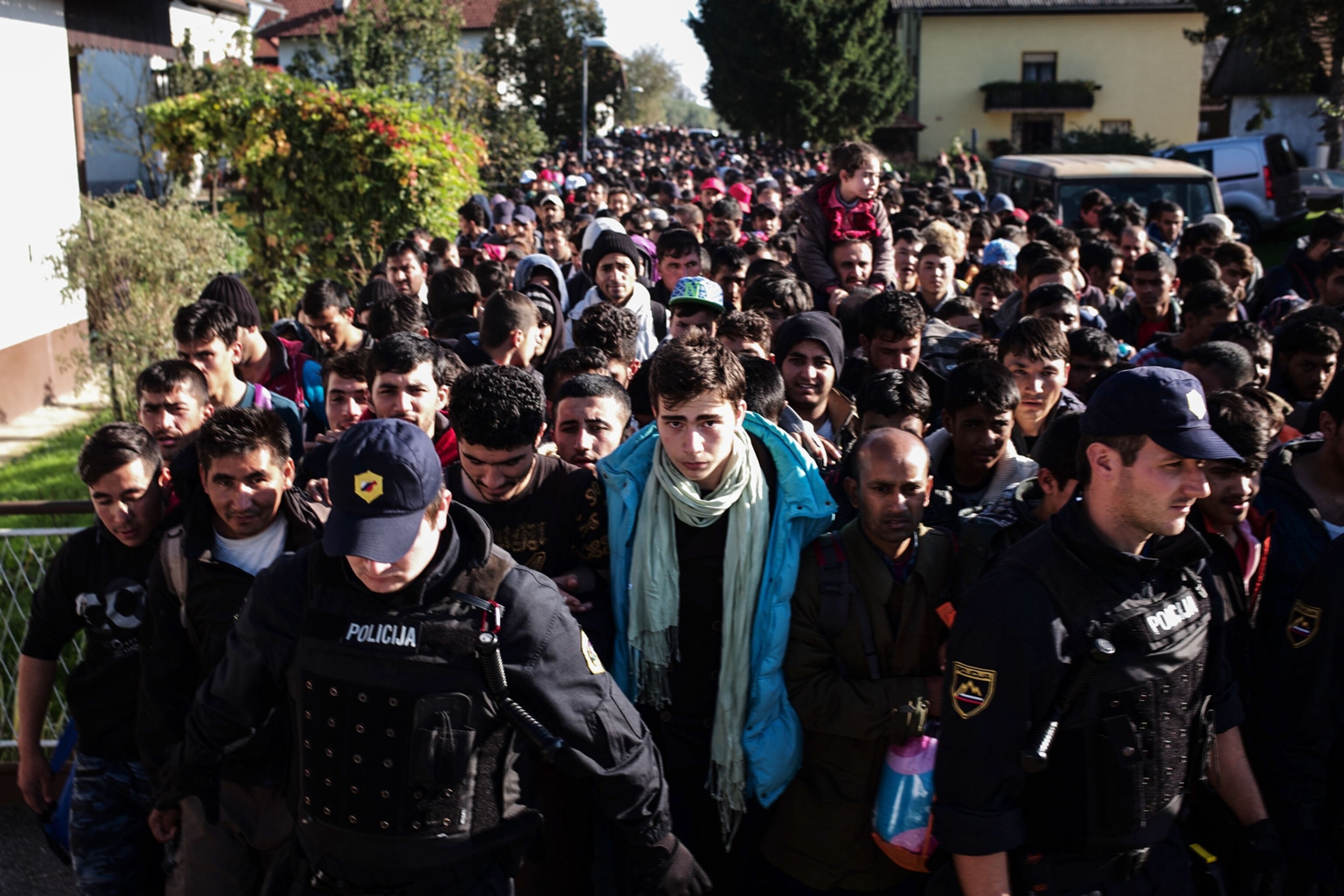 refugees standing behind police in Slovenia