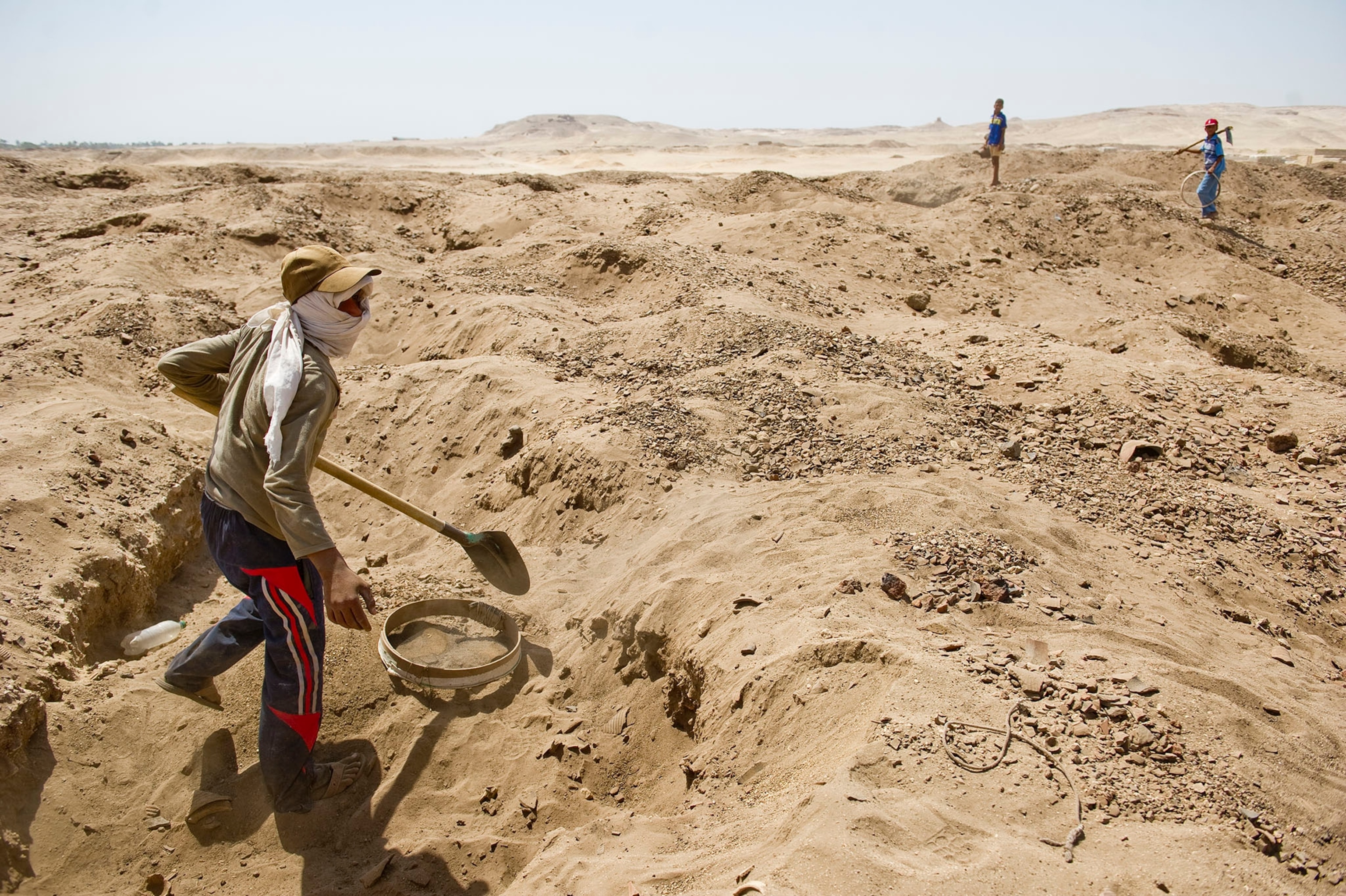 Looters dig through the sand, sifting and unearthing Roman and Pharaonic antiquities to sell on June 26, 2013 in Sheikh Ibada, Egypt.