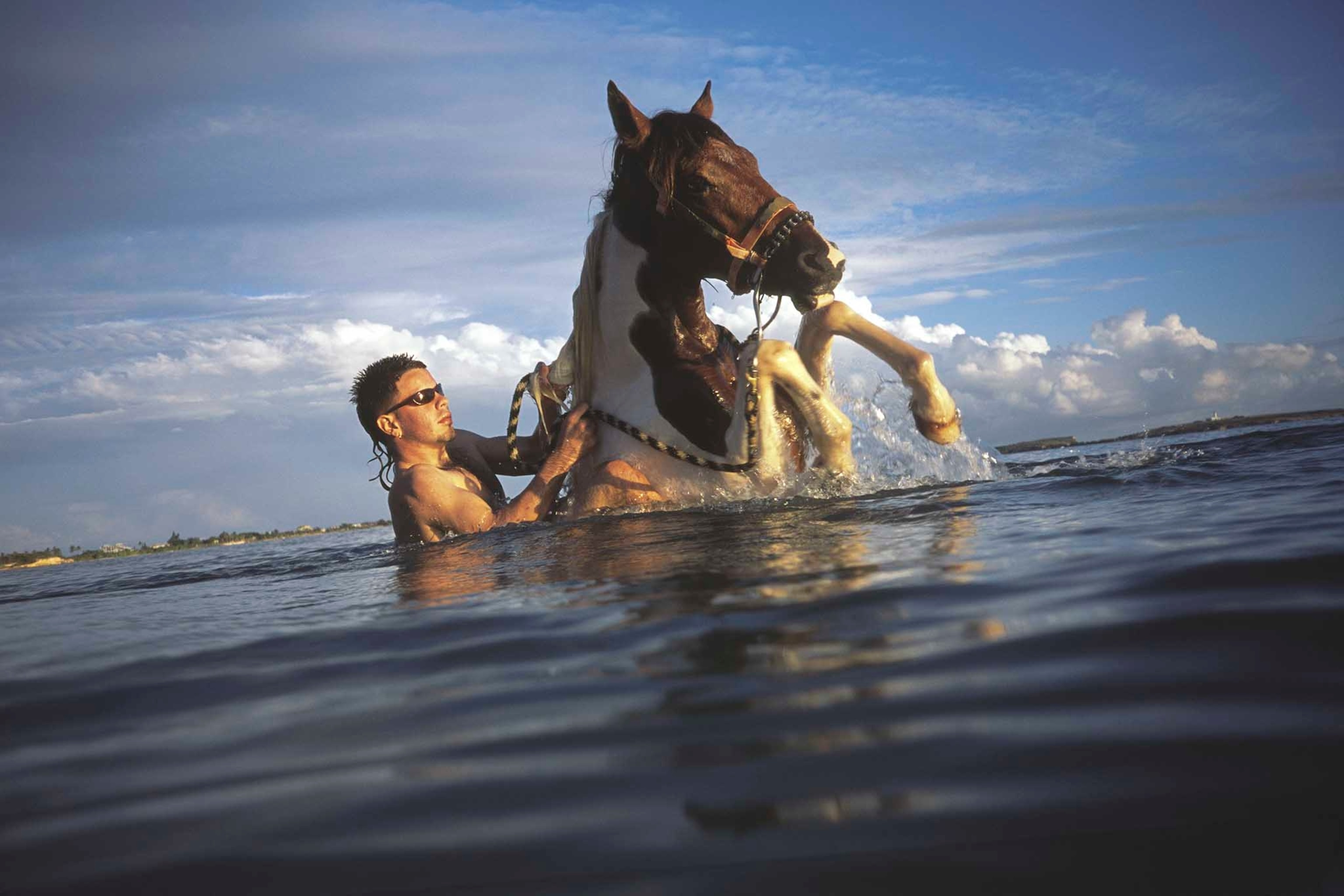 man and horse cooling off in water