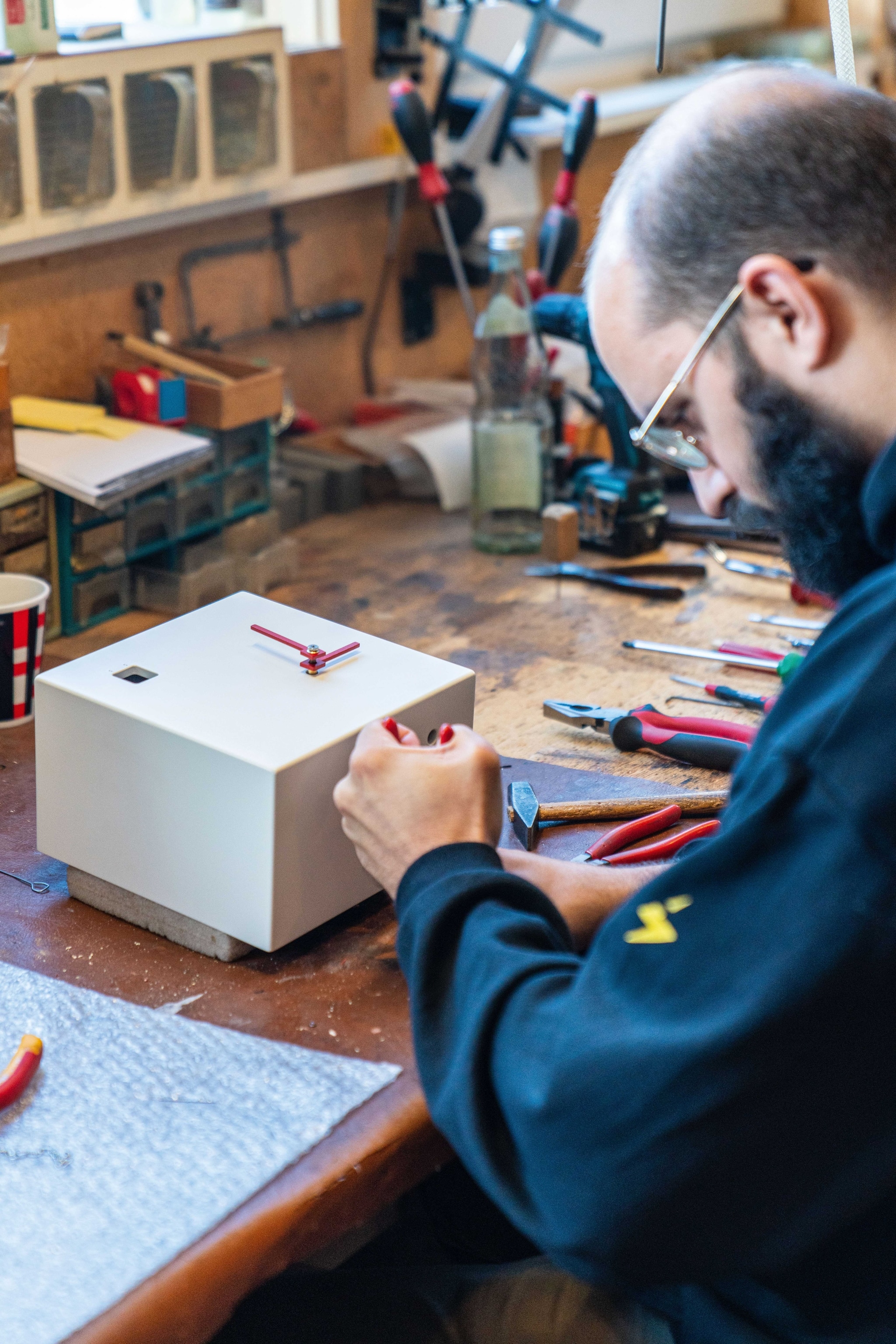 A man works on a cuckoo clock at a workshop.