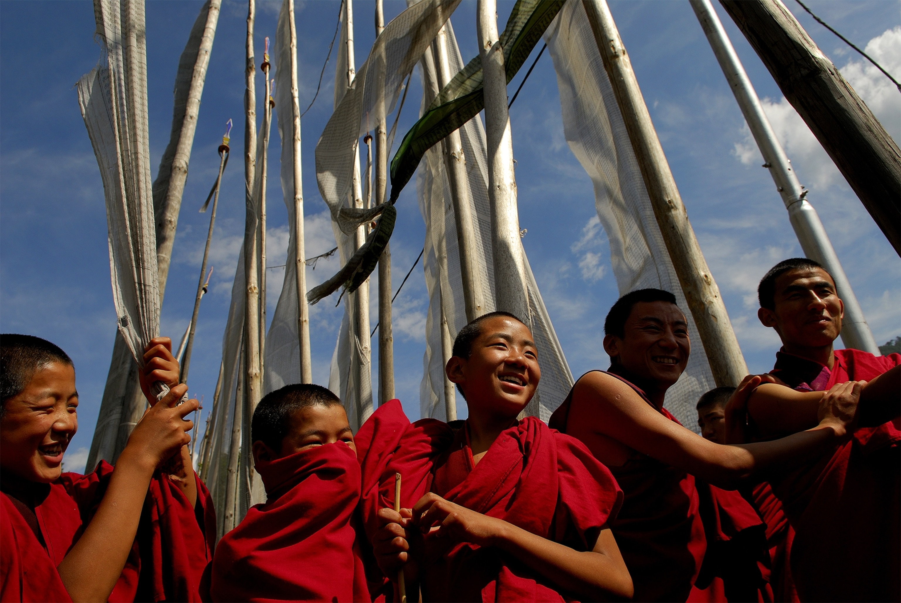 novice monks enjoying a break under prayer flags at Kurjey Lhakhang