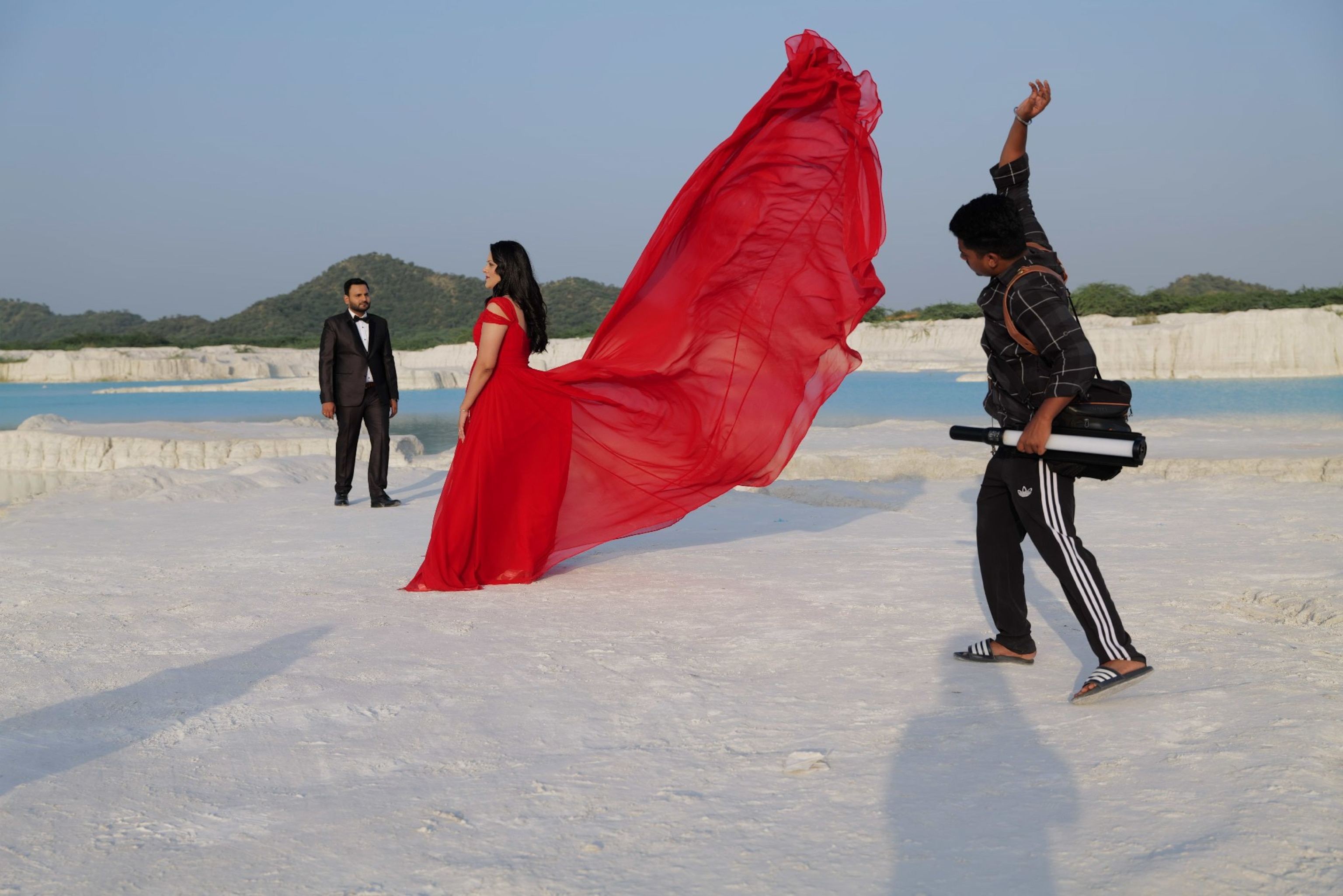 A man throws a dress upward in a dramatic fashion as a woman poses.