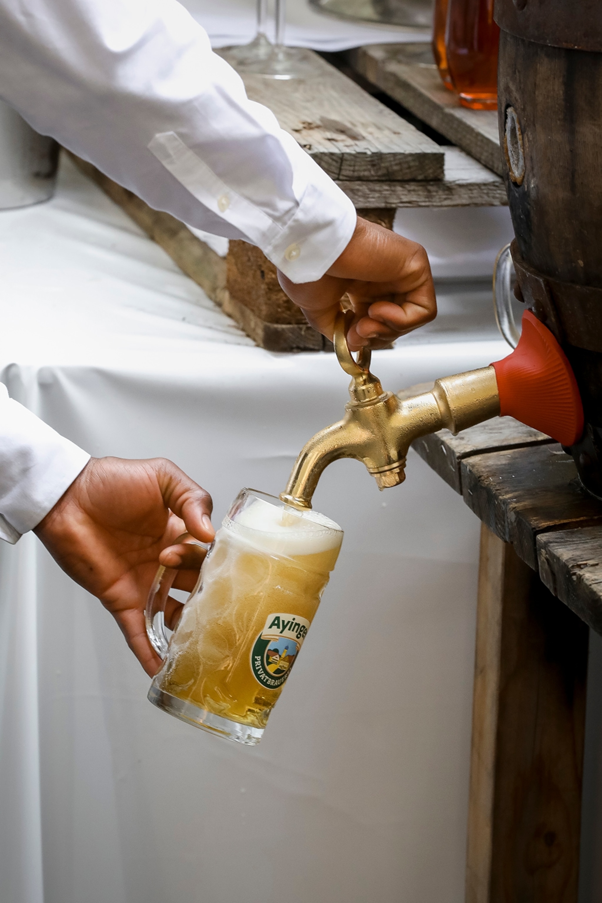 A close-up of a man pouring a mass of beer from a barrel.