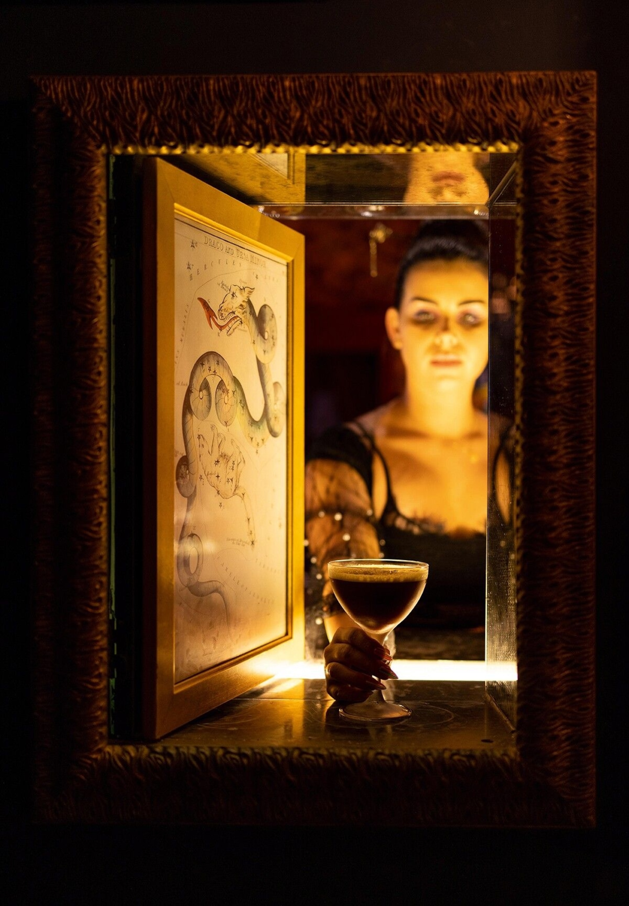 Kiah Darion, general manager of Bar Marilou, serves a la luz cocktail through a hatch in the wall of the ‘speakeasy’ room.