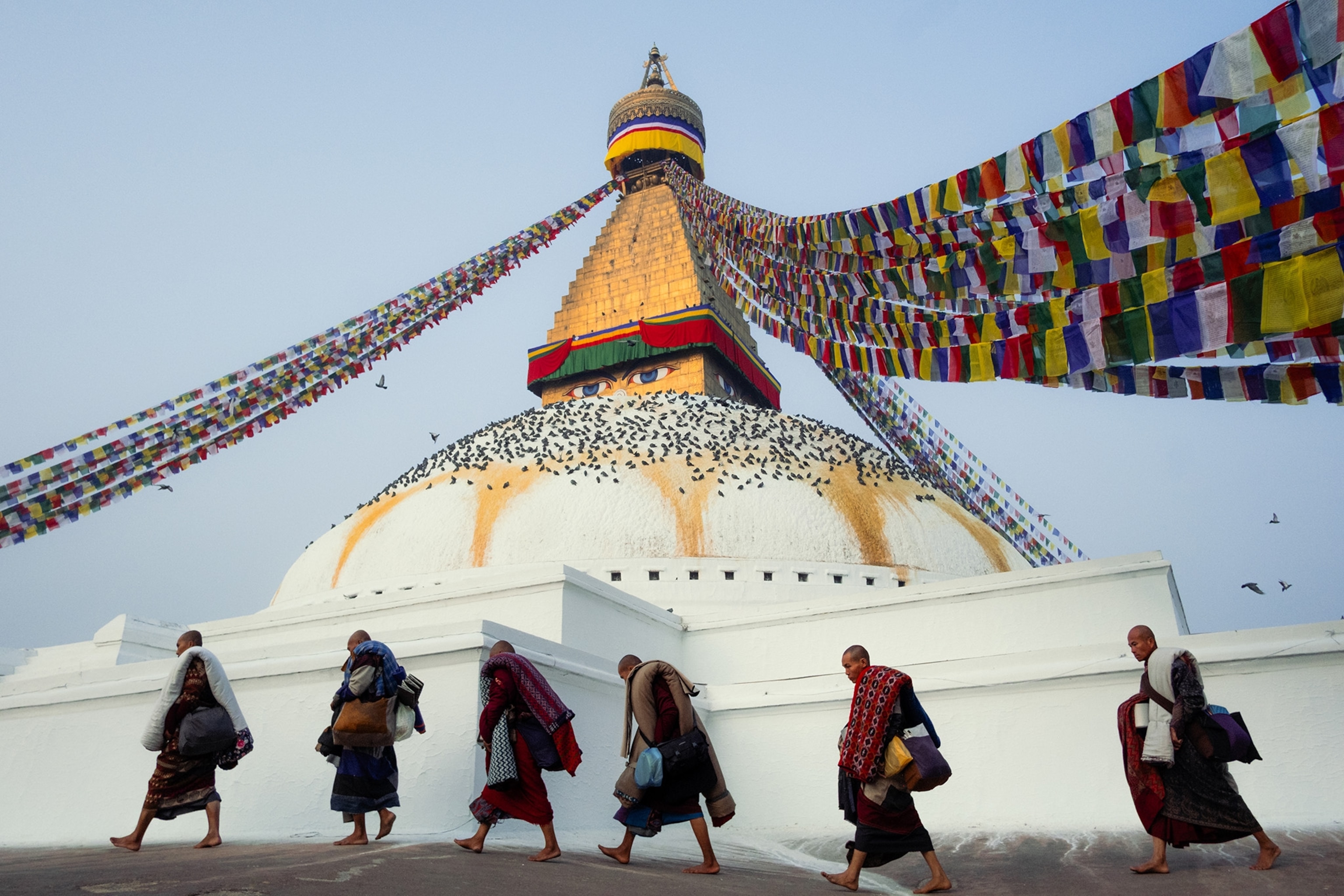 Six people walk around a large white monument with a golden spire.