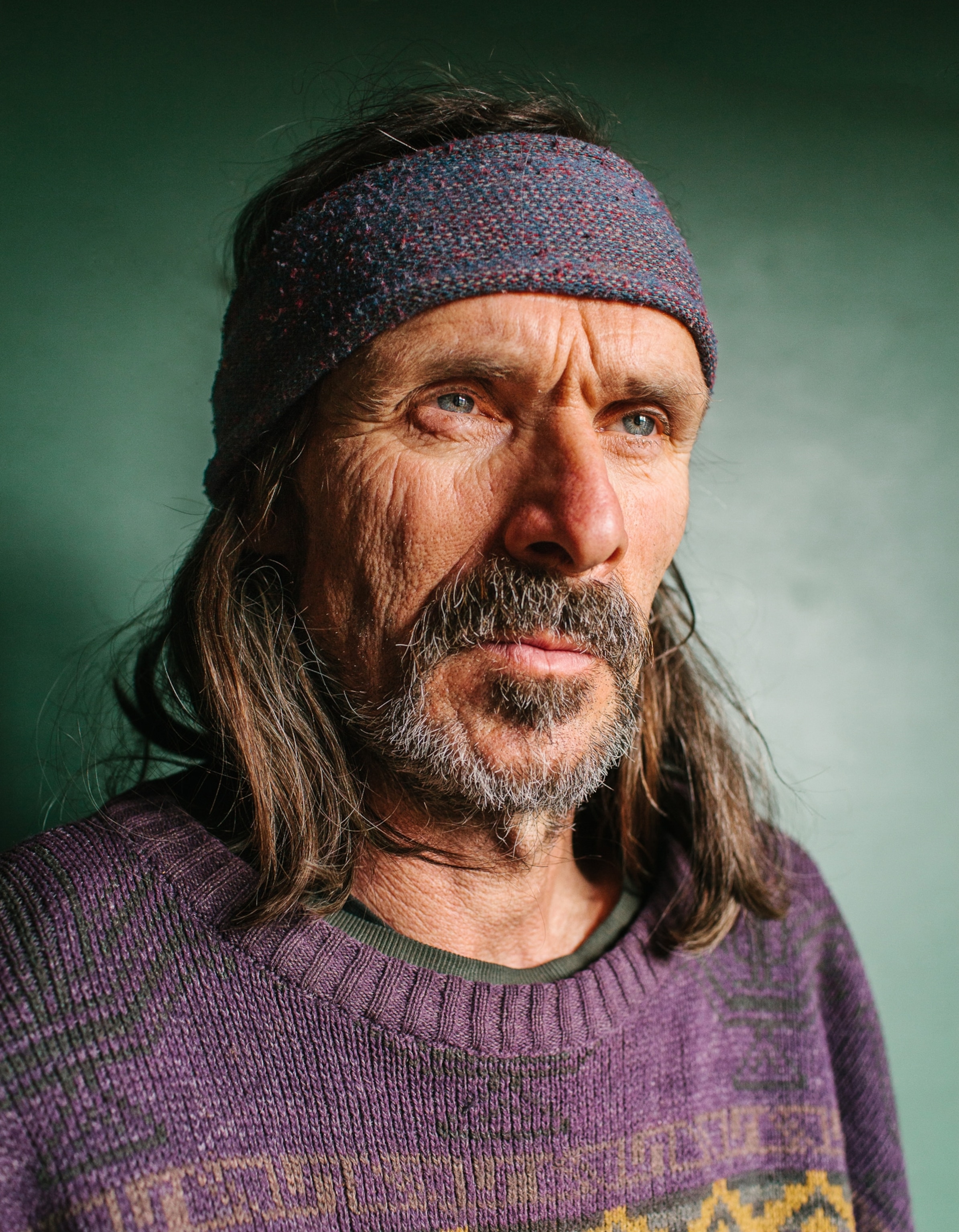 a man with long hair, a mustache, and a serious expression