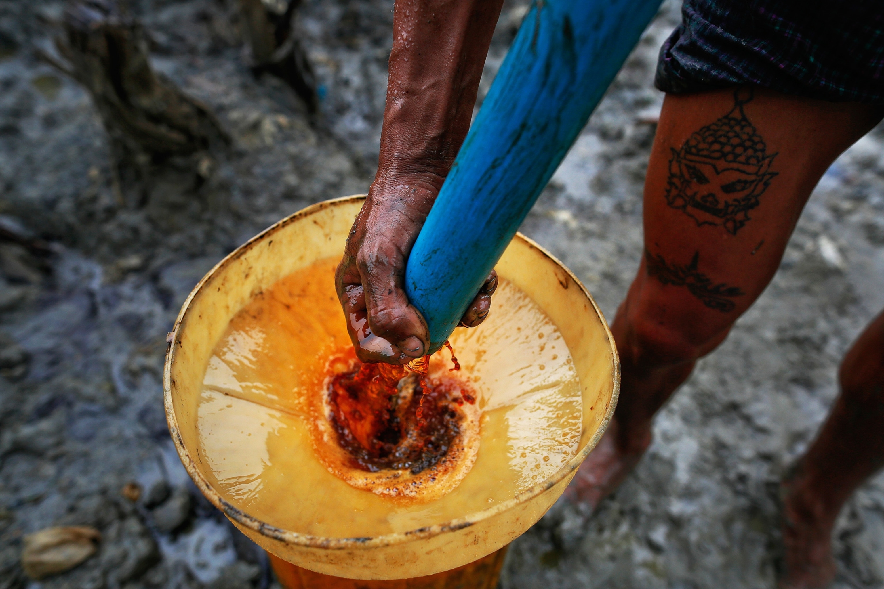 Close-up photo of a man in Myanmar manually extracting oil from a well.