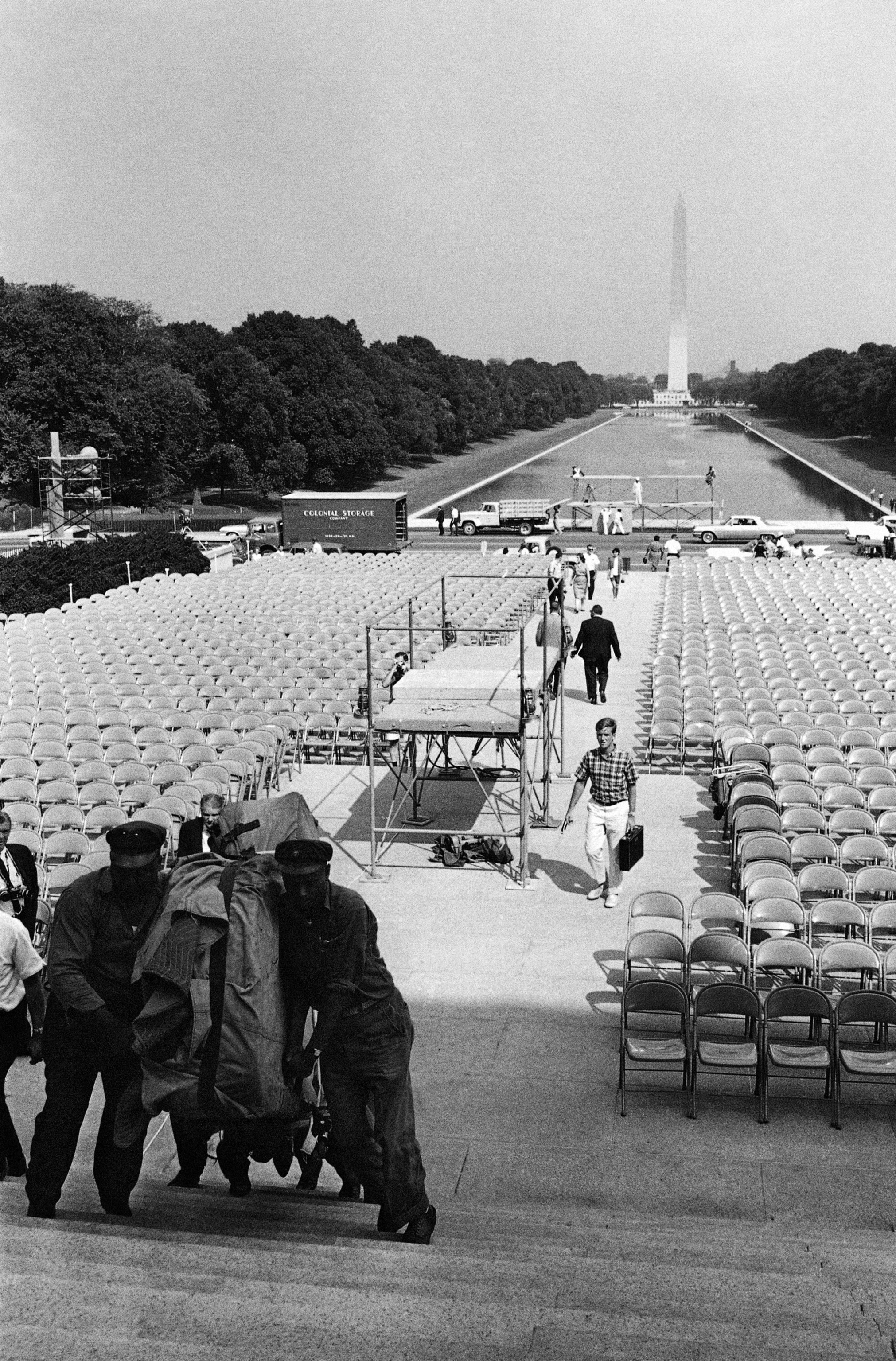 Steps leading to the Lincoln Memorial are packed with chairs for (August 28) March on Washington ceremonies. The stands are for photo and television coverage of the event. In background is the Reflecting Pool and the Washington Monument, August 27, 1963. In left foreground workmen move a piano into the Memorial for use with mass singing. (AP Photo)