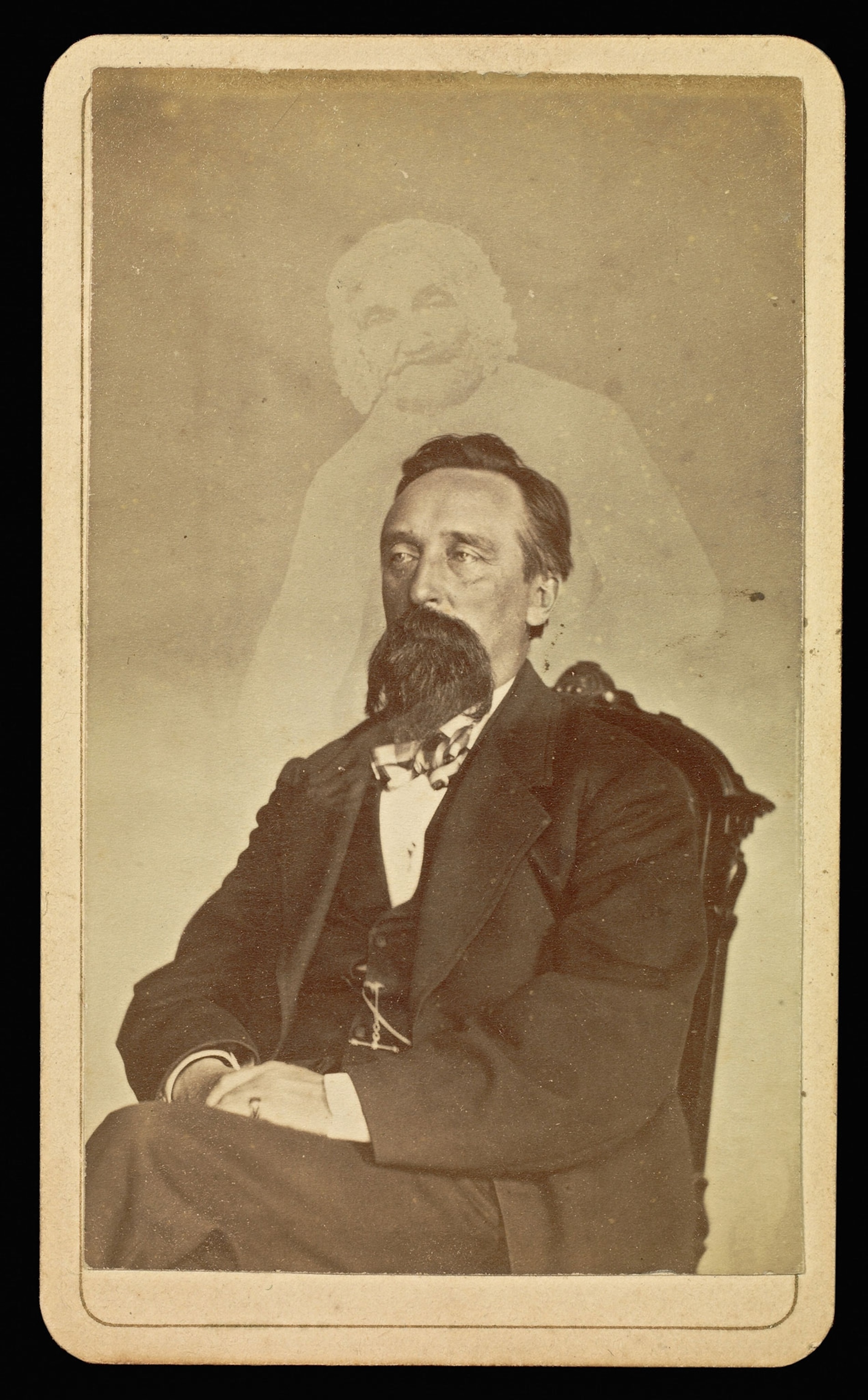 Portrait of a seated bearded man, with a faint image of an old woman above him.