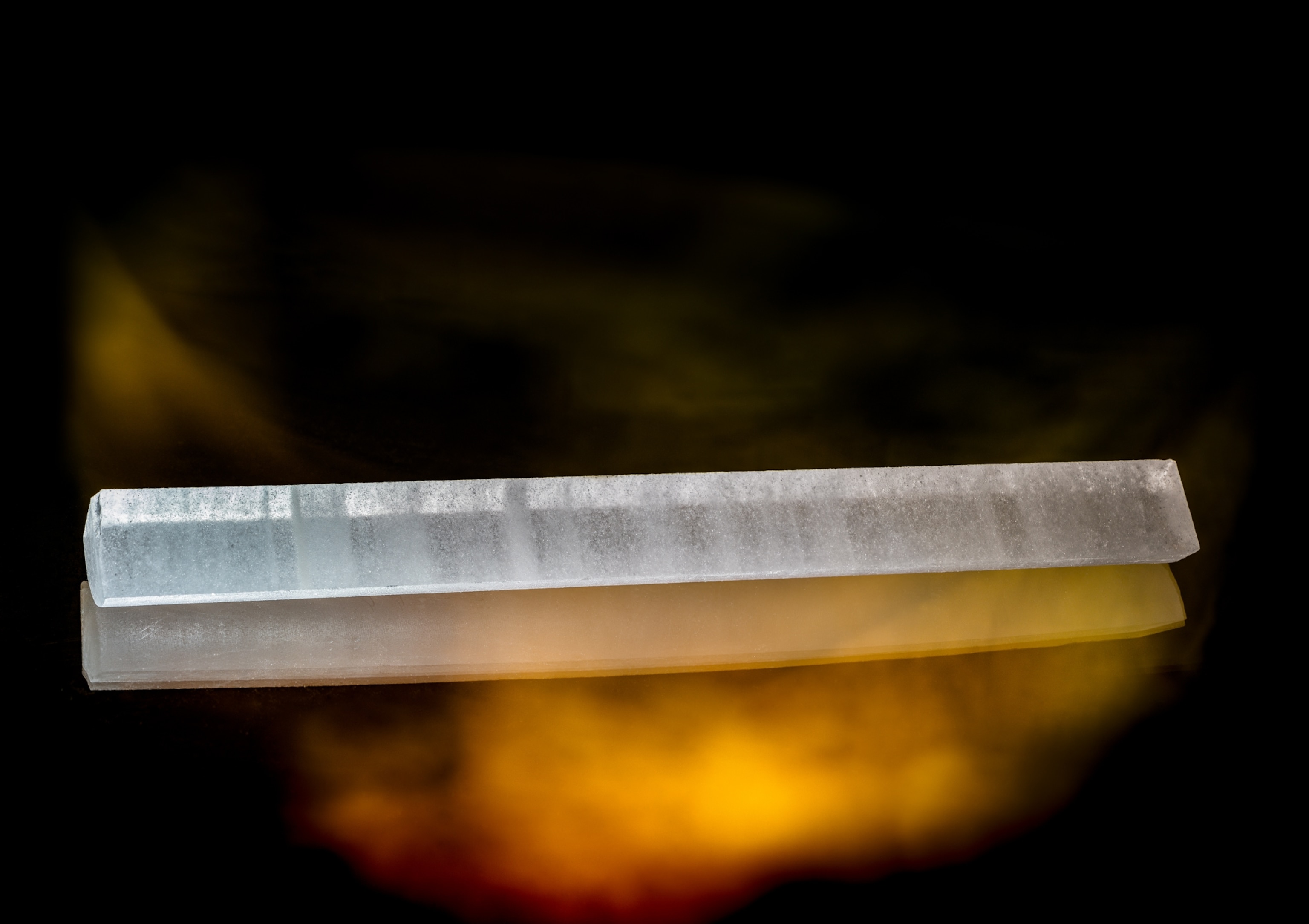 Two long blocks of ice, one is visible and another one appears like a shadow in golden glow.