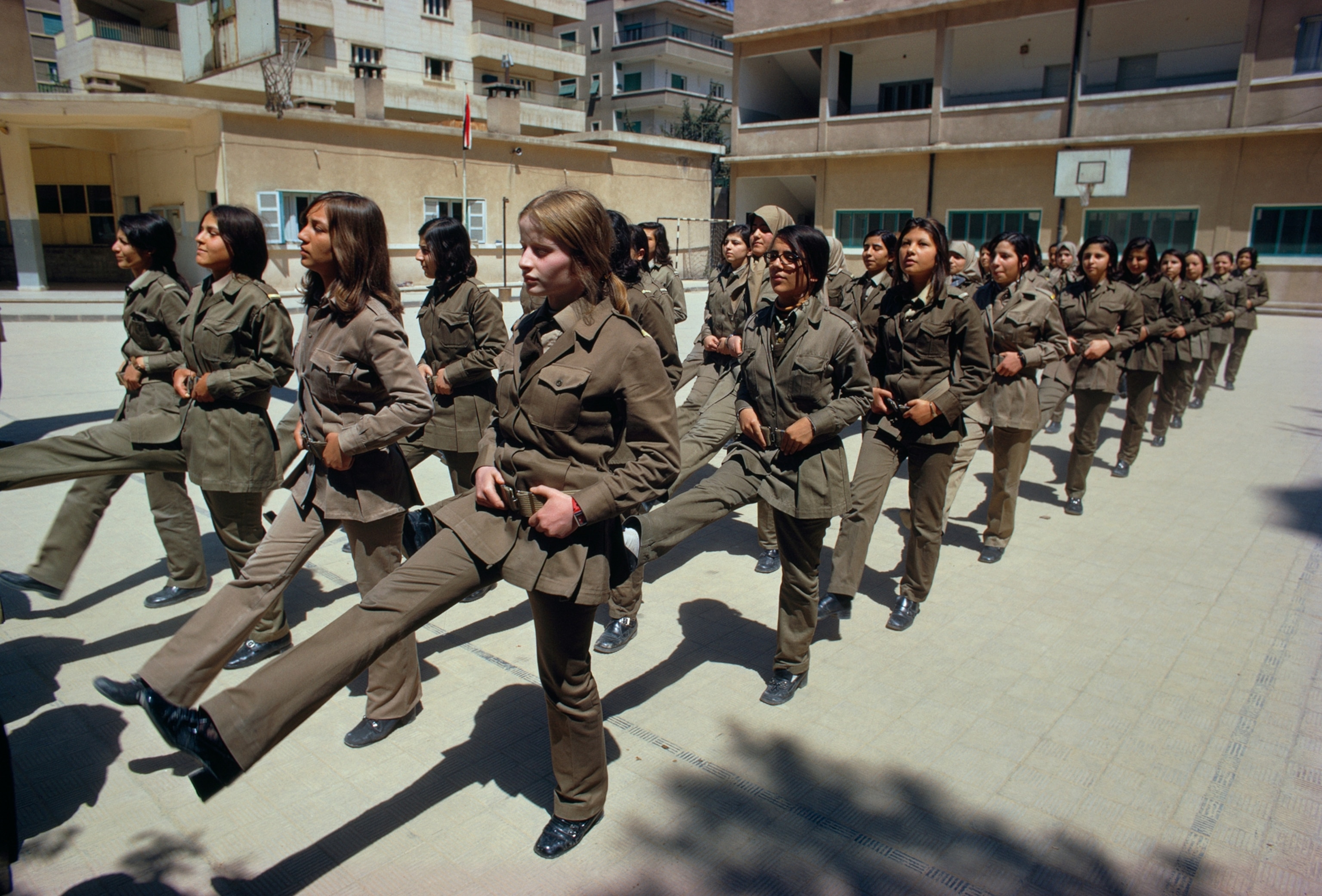 Lines of teenage girls in military dress march, 1974