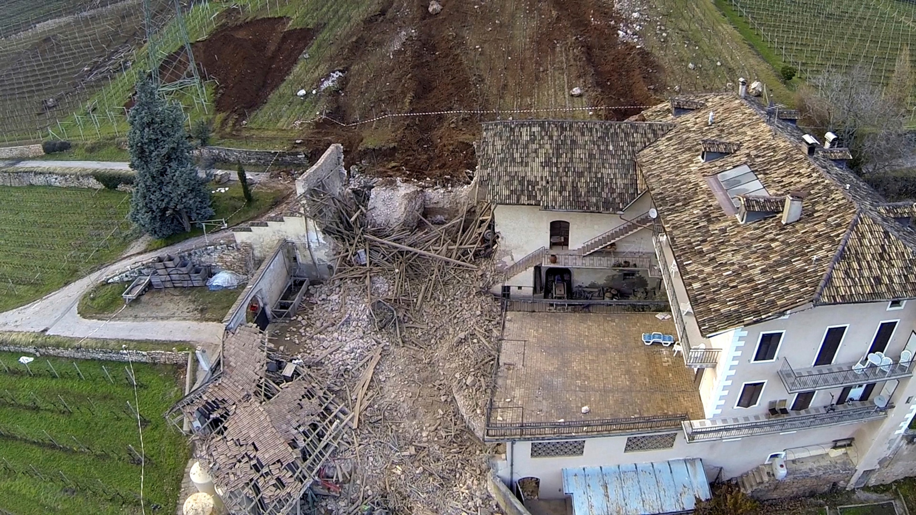 In this photo provided by Tareom.com Thursday, Jan. 30, 2014, and taken on Jan. 23, 2014, a huge boulder is seen after it missed a farm house by less than a meter, destroying the barn, and stopped in the vineyard, while a second giant boulder, which detached during the same landslide on Jan. 21, 2014, stopped next to the house, in Ronchi di Termeno, in Northern Italy.