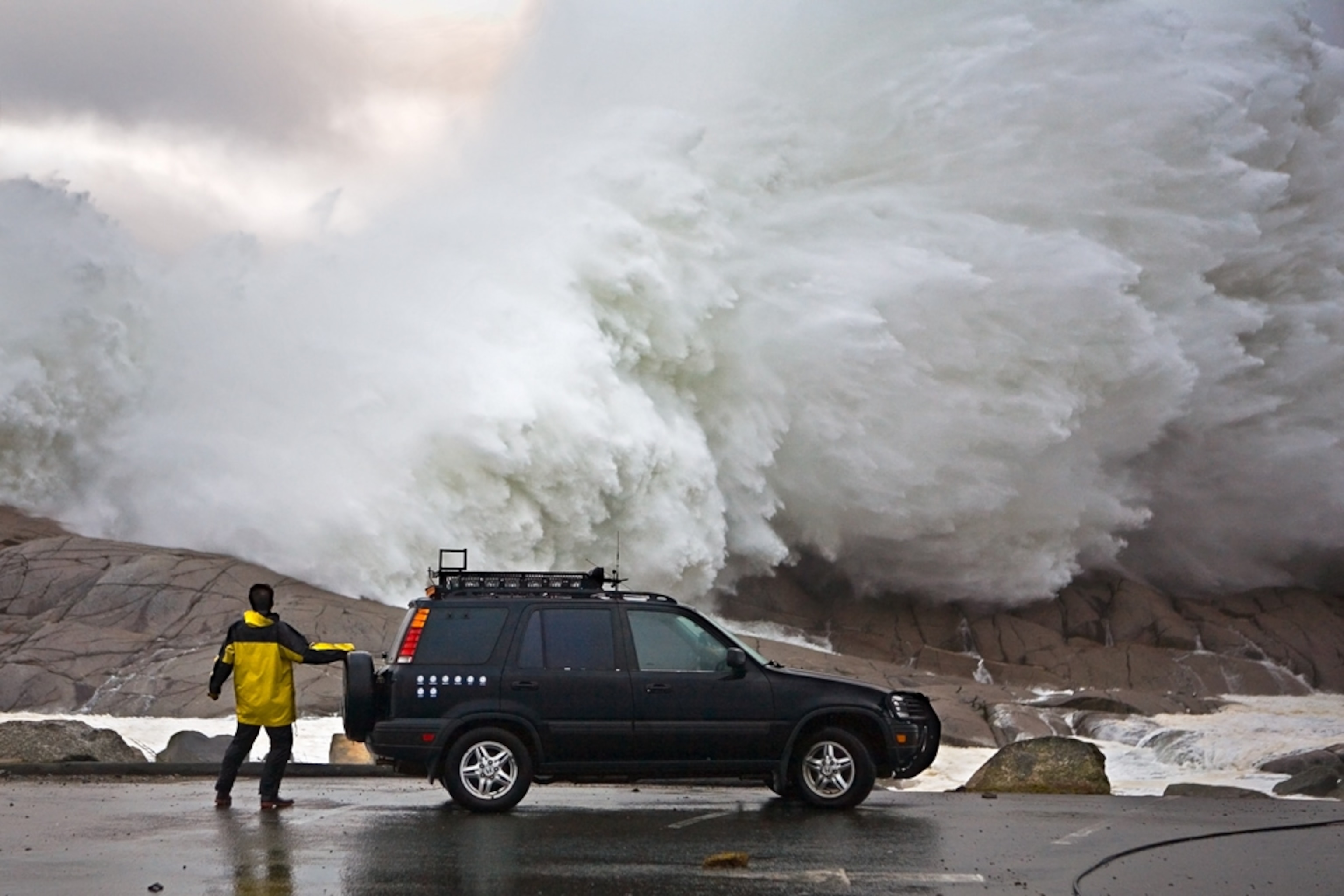 A 50-foot wave crashes into a seawall by a man during Hurricane Noel.
