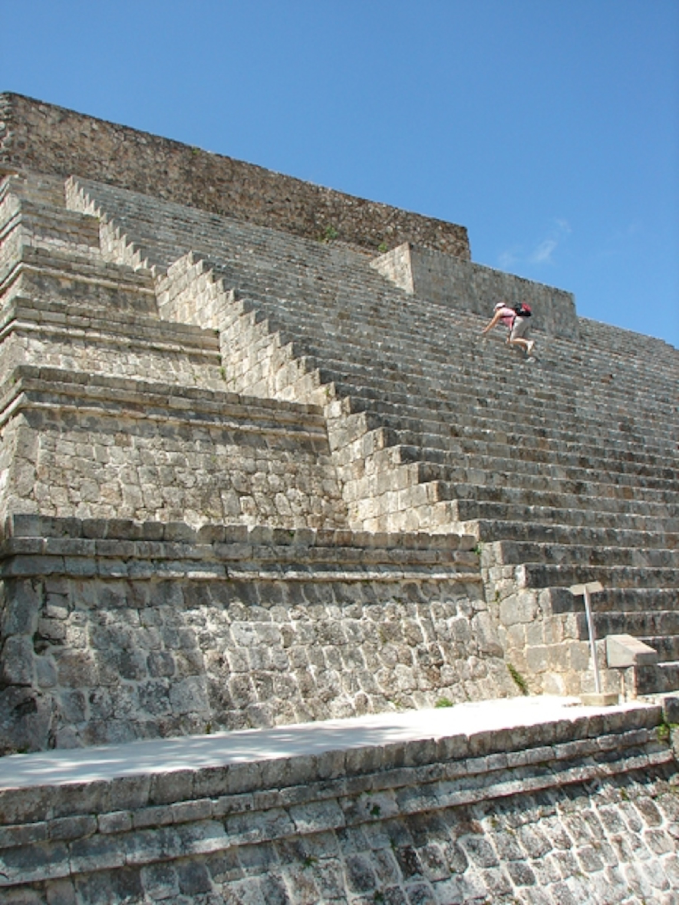 a tourist climbing Maya ruins at Uxmal