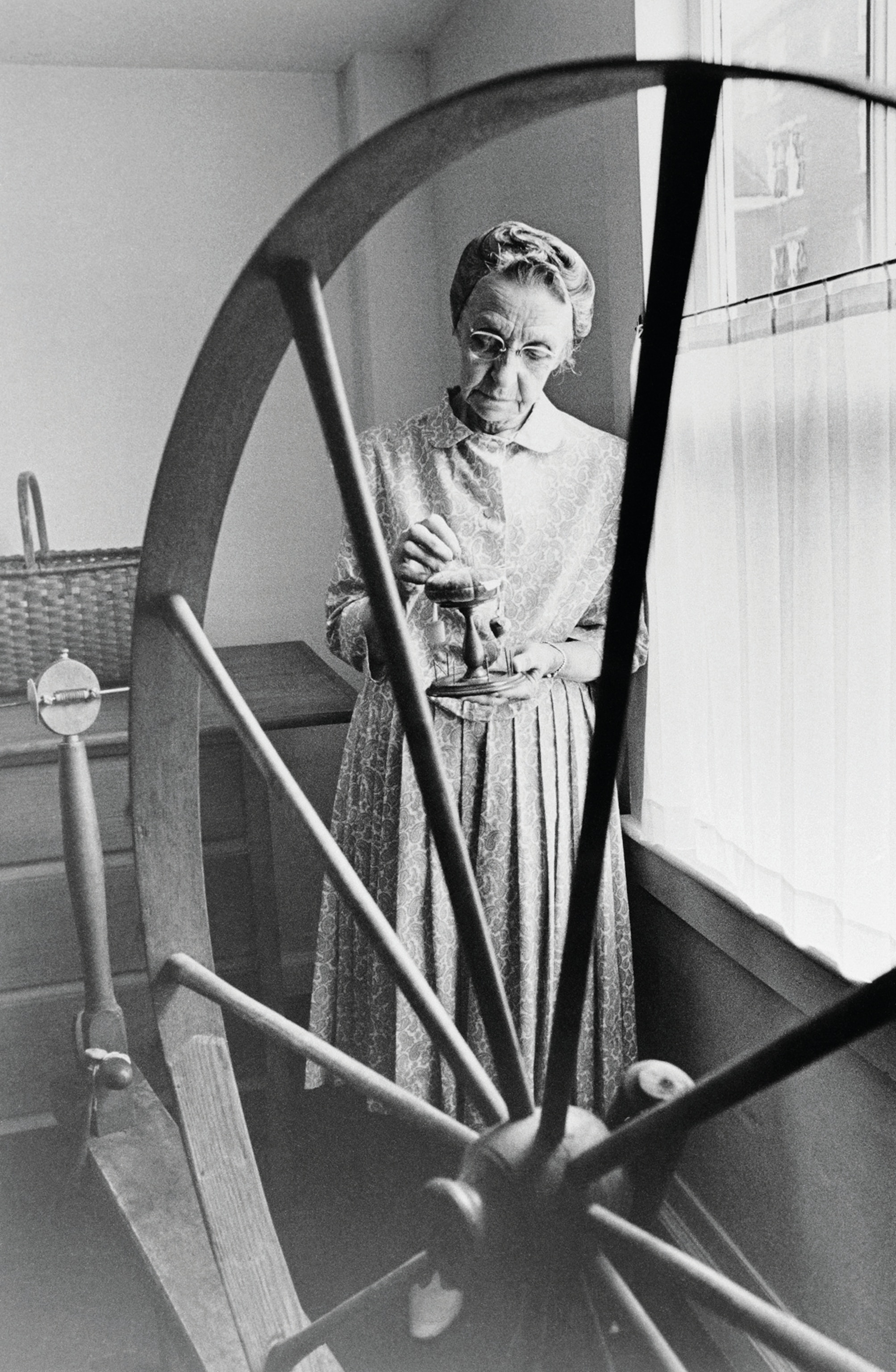 Sister Mildred, framed by a spinning wheel, in a photo taken shortly before an auction of Shaker-made goods.