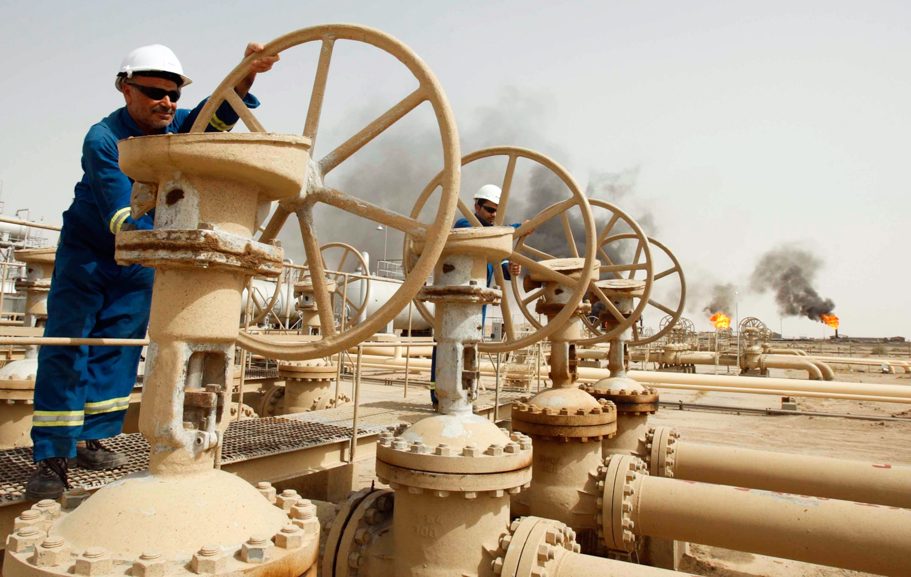 Iraq oil picture - oil workers turn a valve at the Zubair oil field in Basra, Iraq.