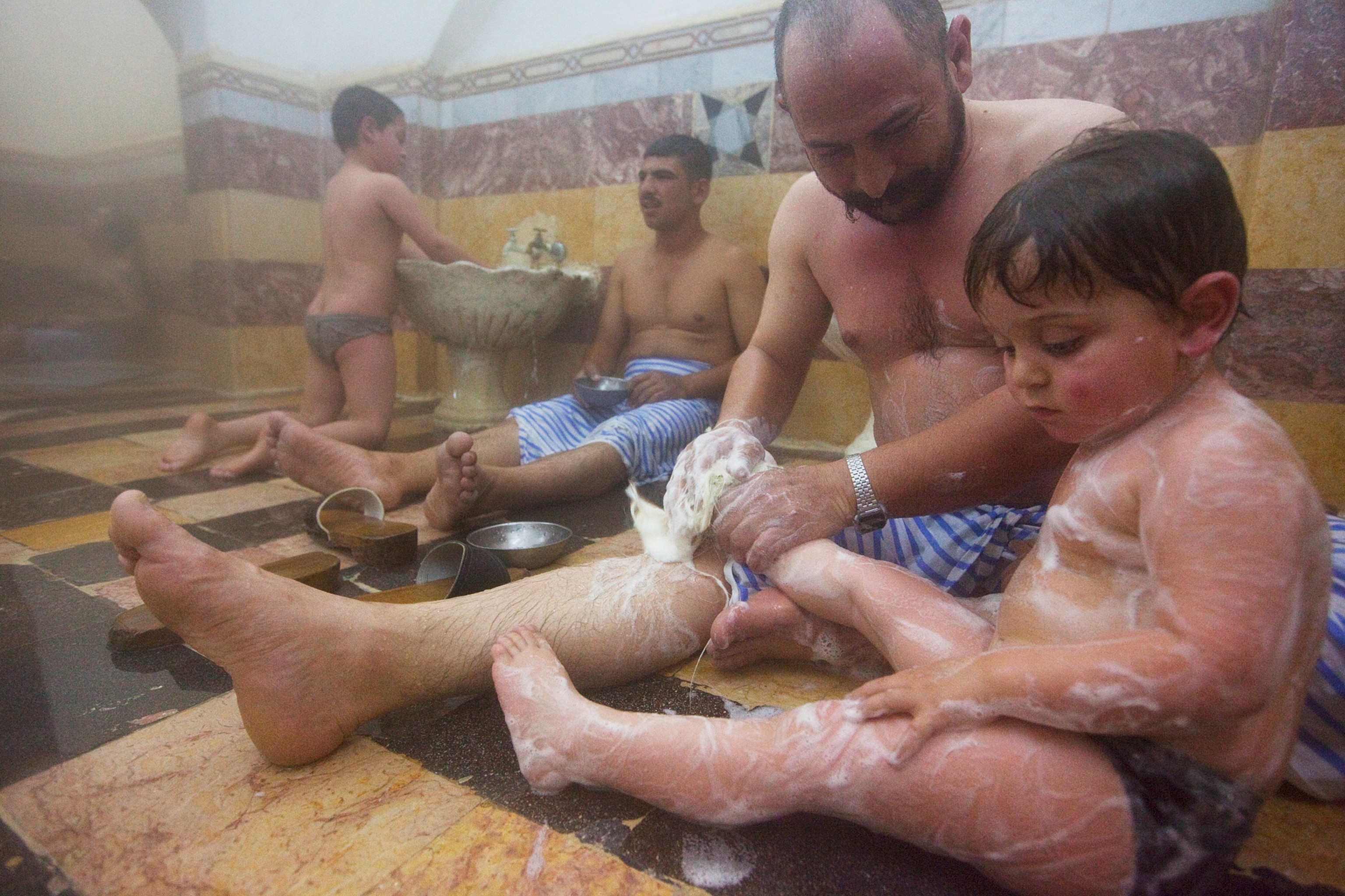 Two boys and their fathers in an ancient bathhouse, 2009