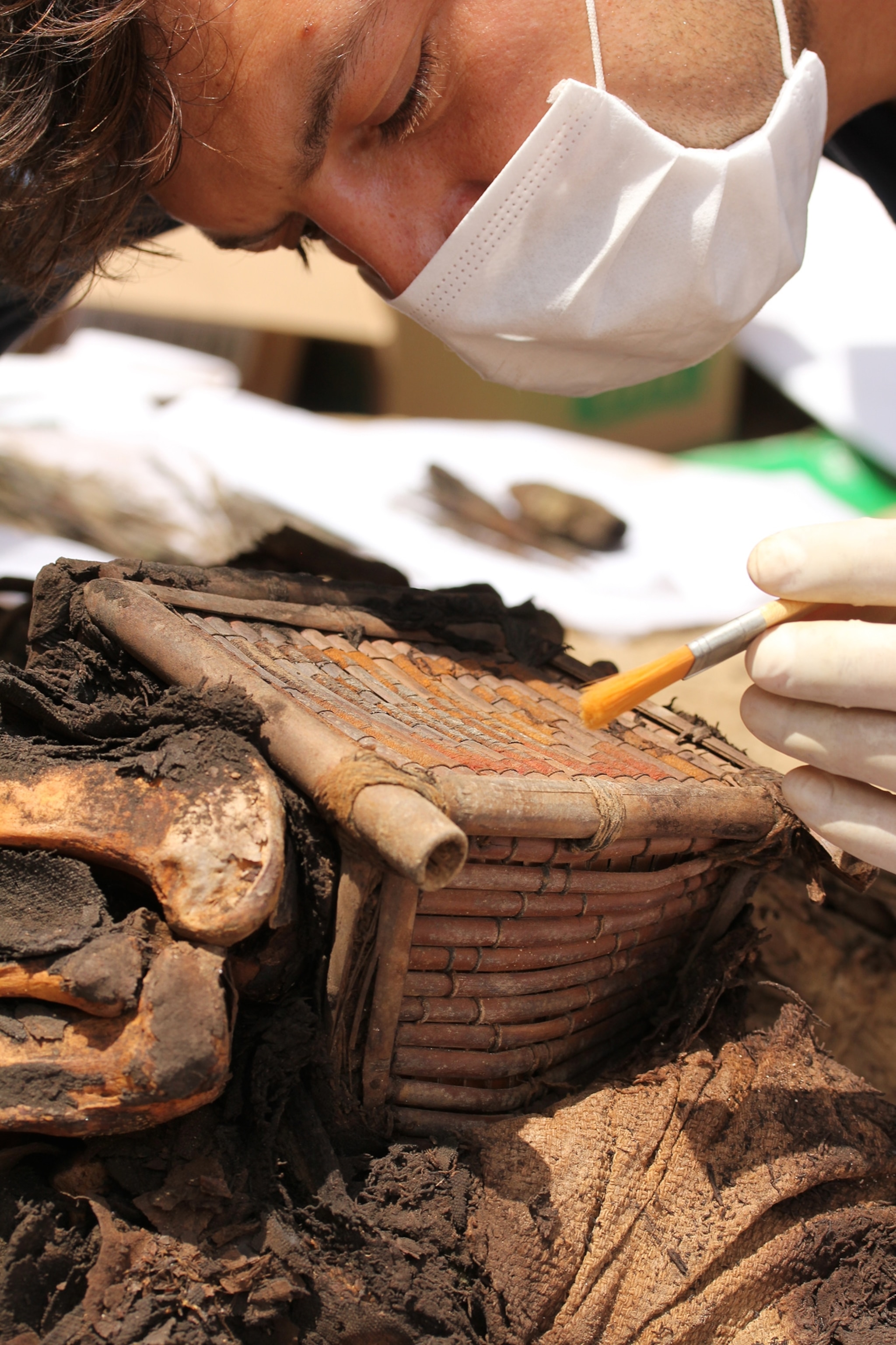 Peru Tomb - An archaeologist brushes away sediment from a box.