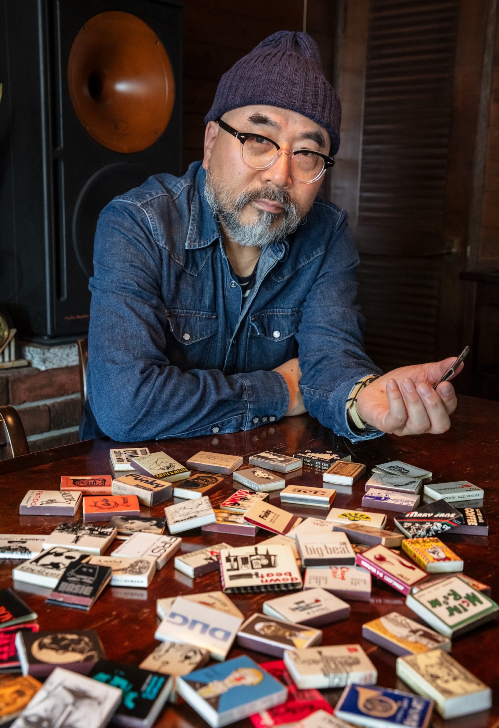 Man with collection of Jazz kissa matchbooks on the table before him.