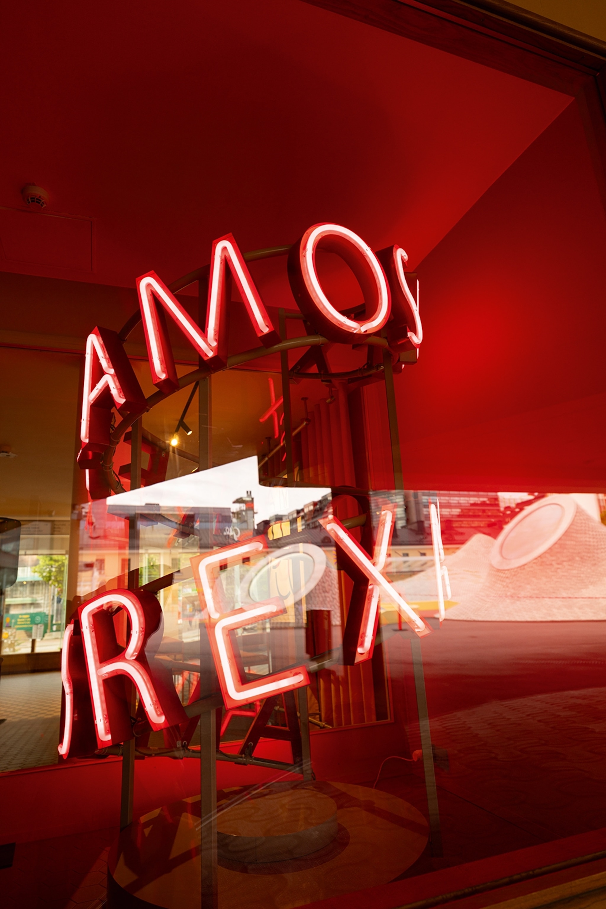 The interiors of a modern art gallery with neon lettering wrapped around a steel sculpture.