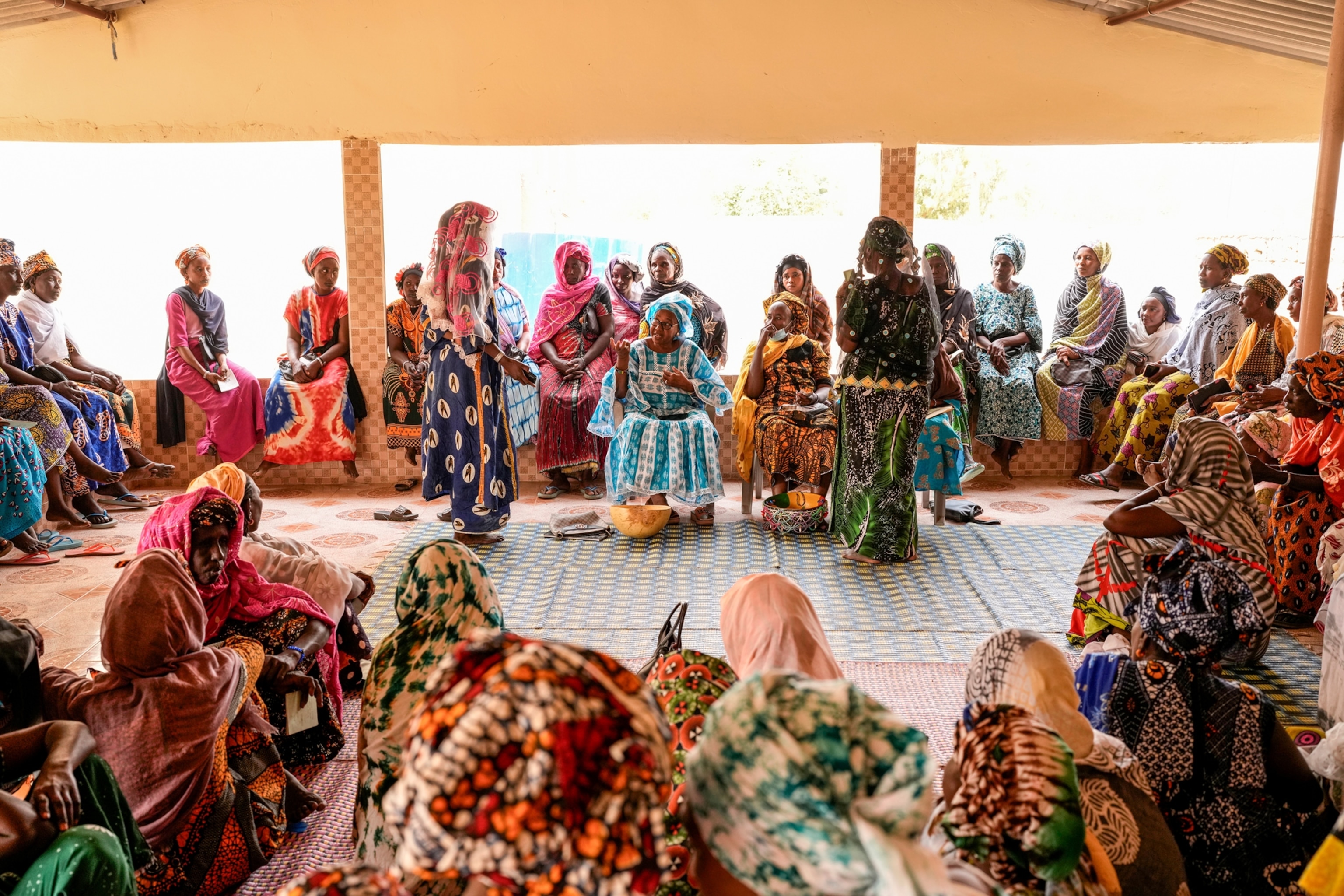 Women gather in a circle around three seated women.