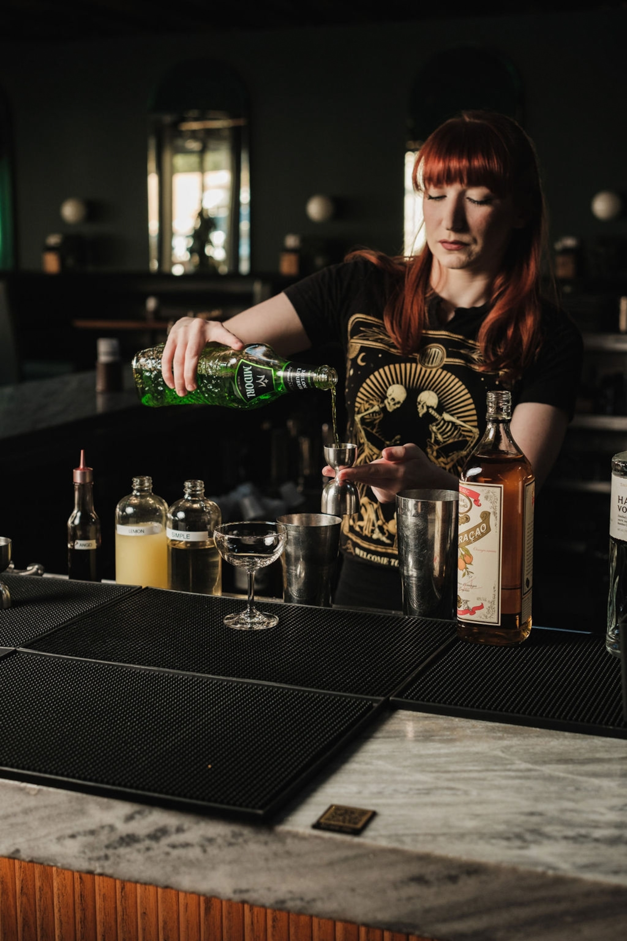 A bartended measuring out liquor for a cocktail