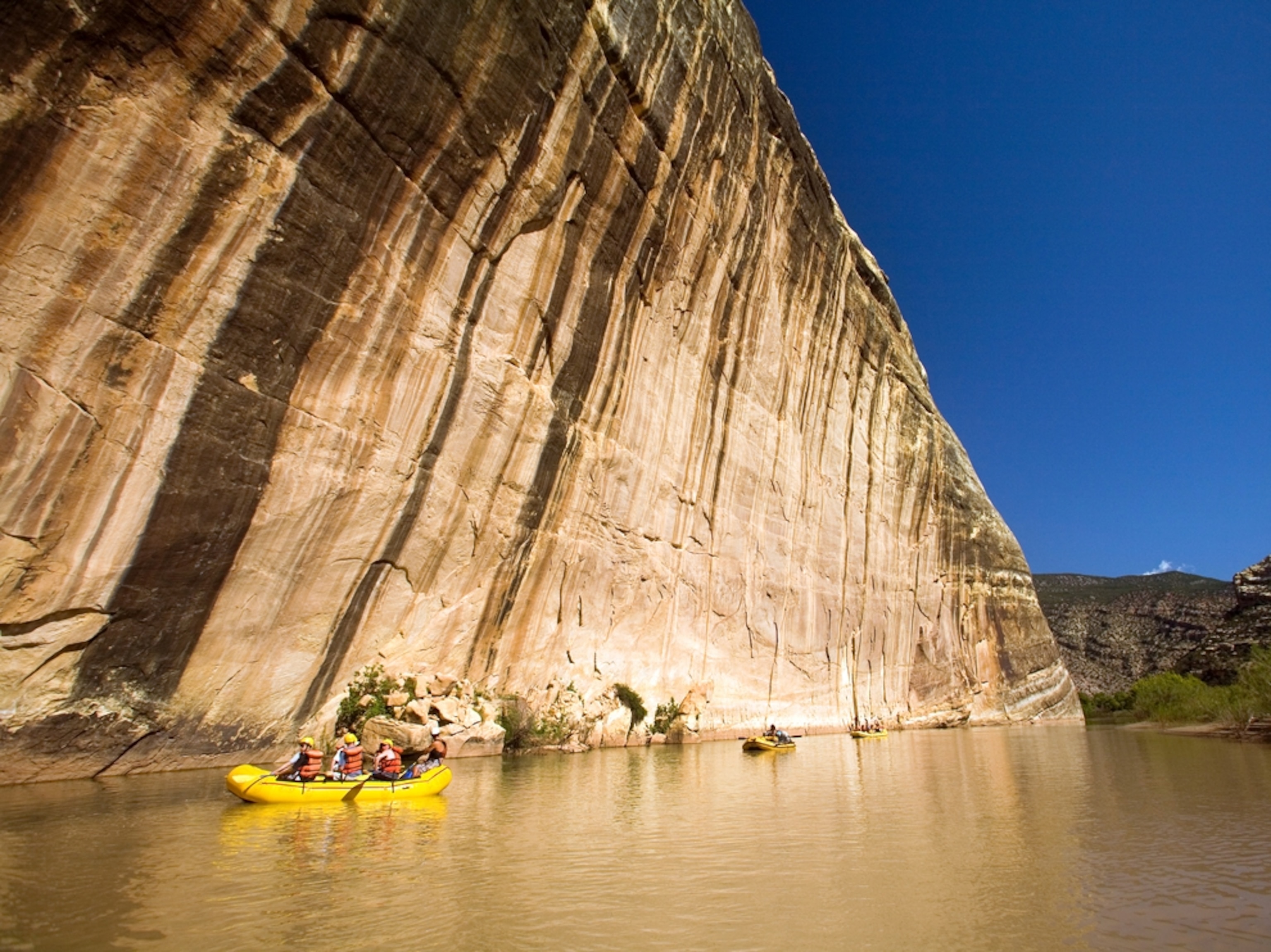 Boaters floating past huge rock face