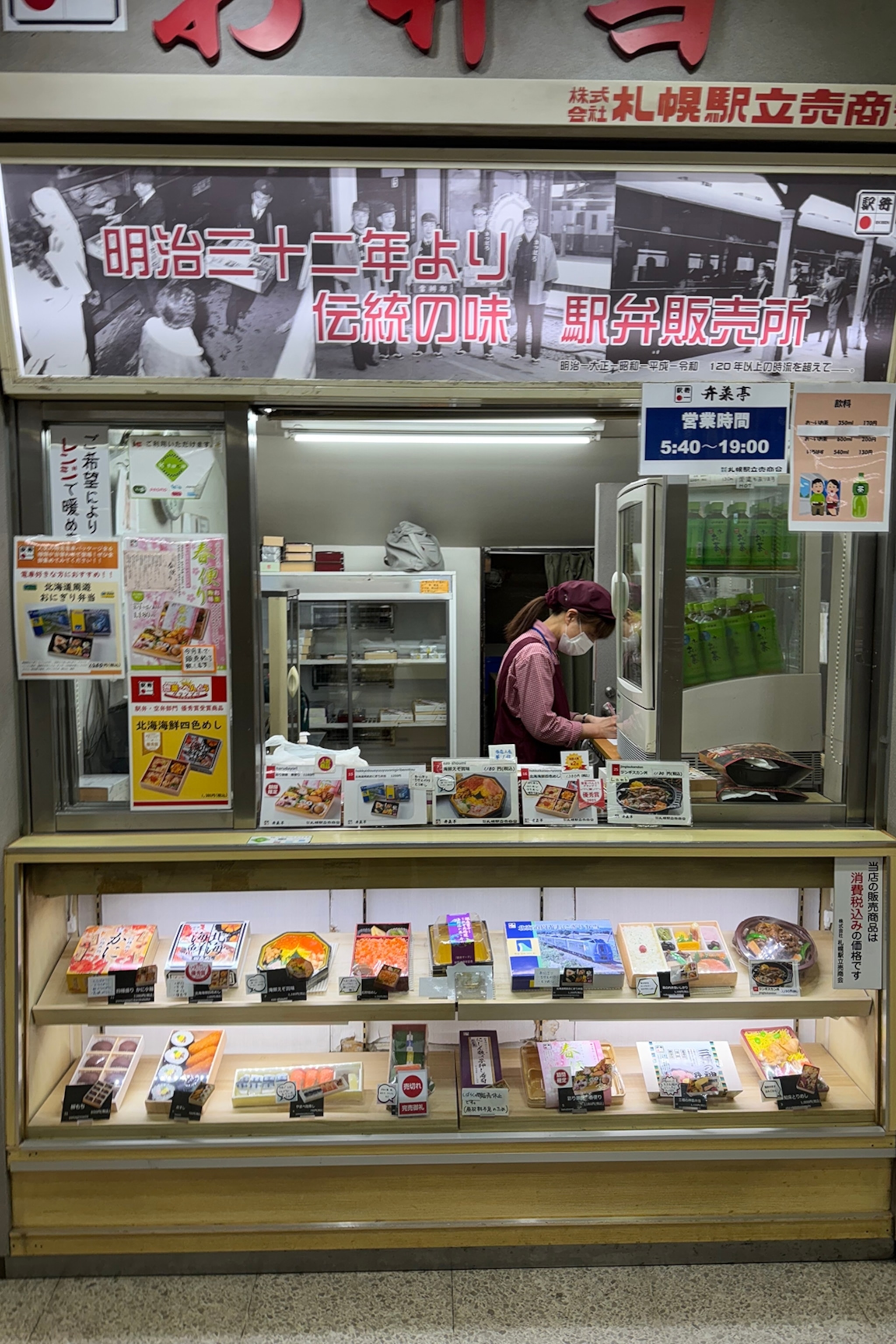 A hole-in-the-wall stand selling train lunch boxes in a train station.