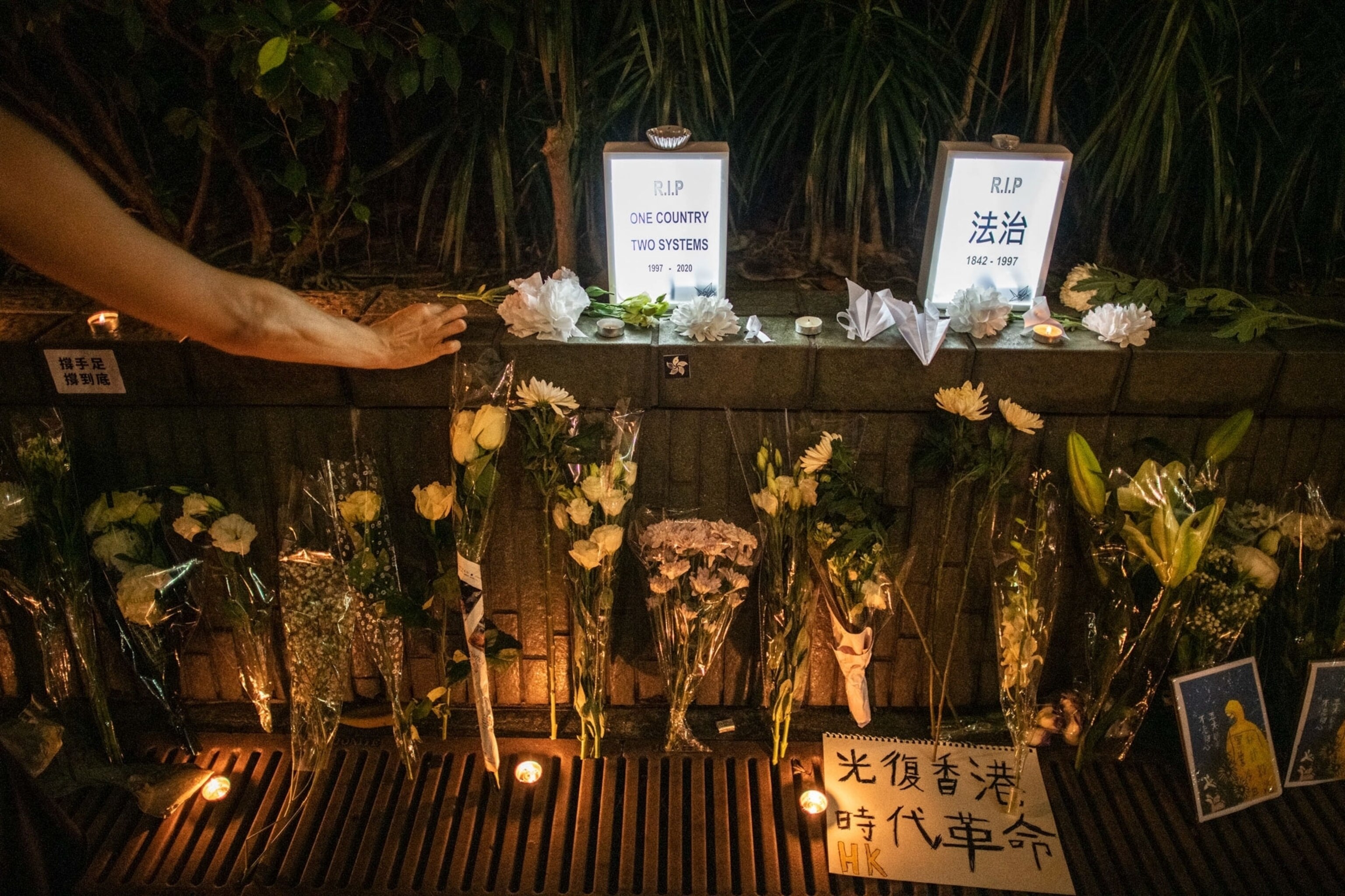 people setting flowers at a memorial in Hong Kong