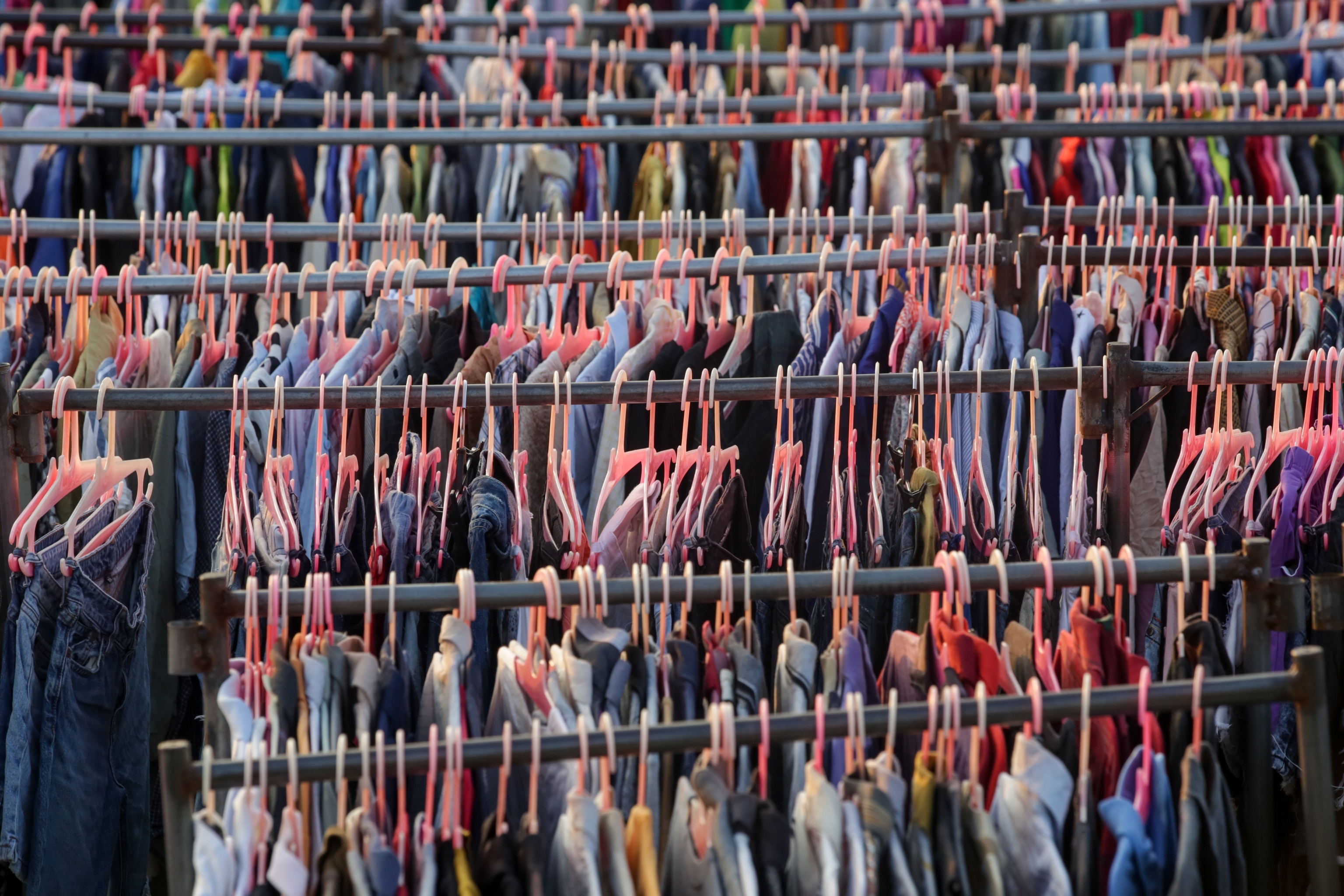 rows of clothing hanging on plastic pink hangers.
