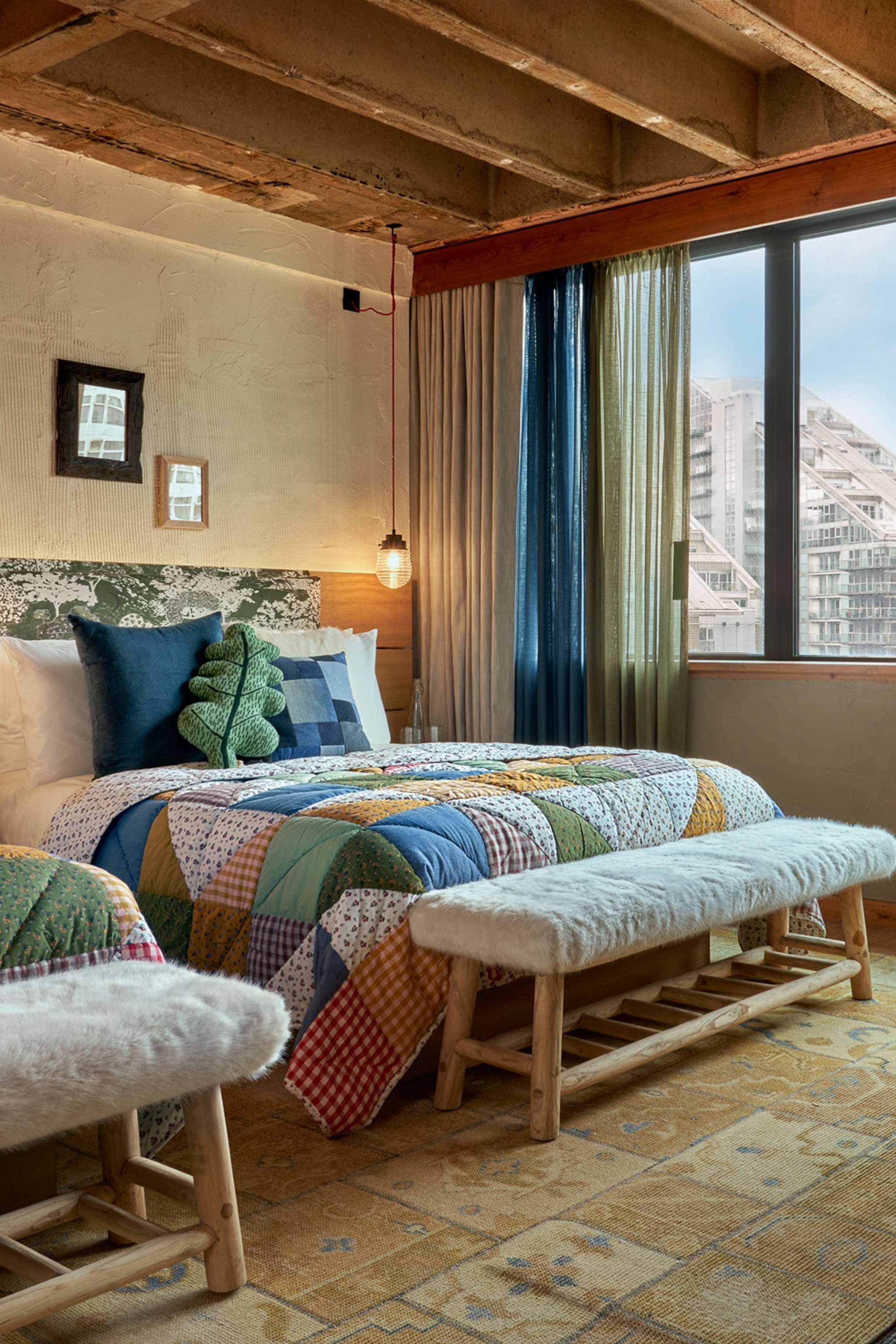 The interiors of a hotel bedroom with wooden furnishings and views over Manchester.