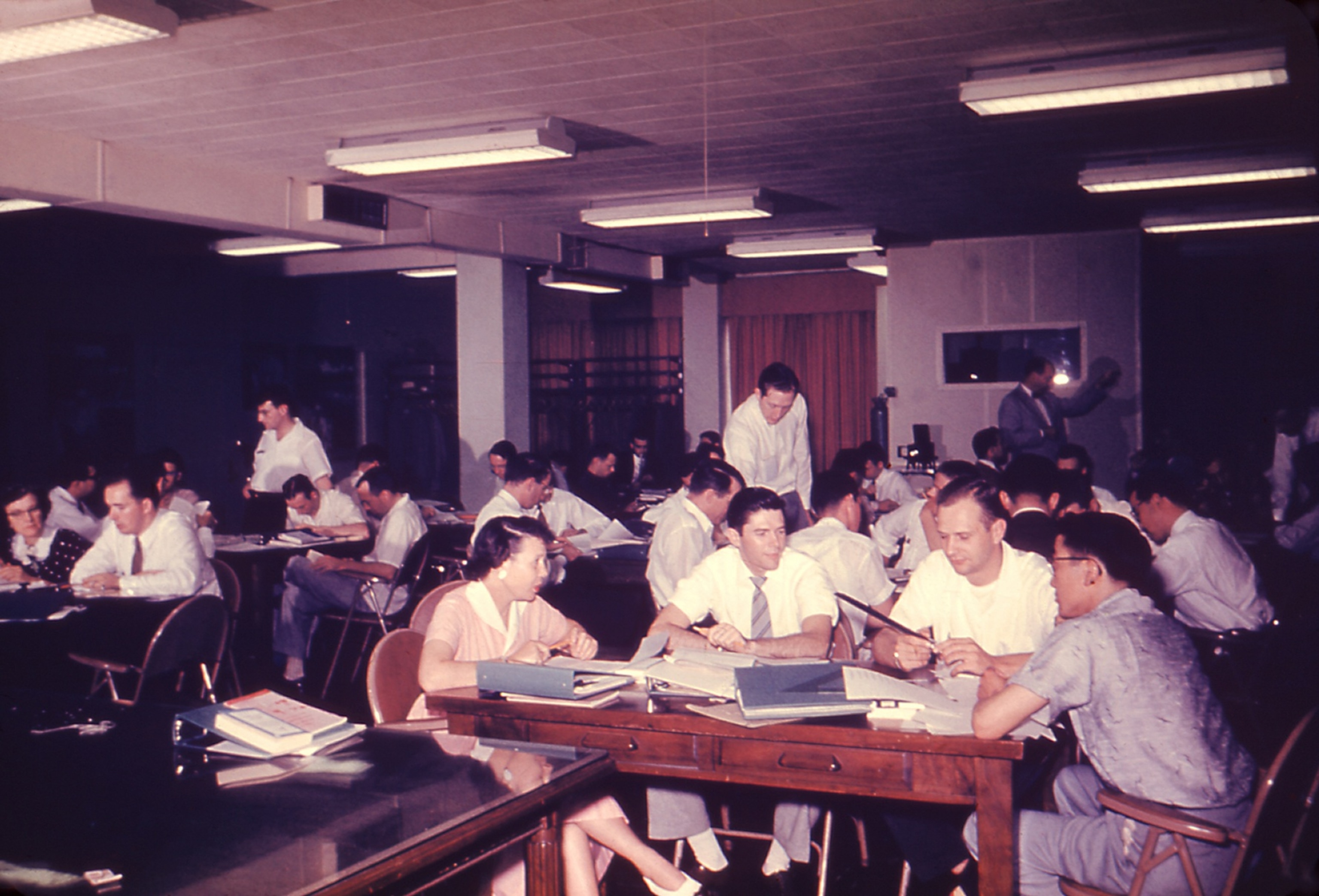 Men and women gathered around wooden tables engaged in discussions