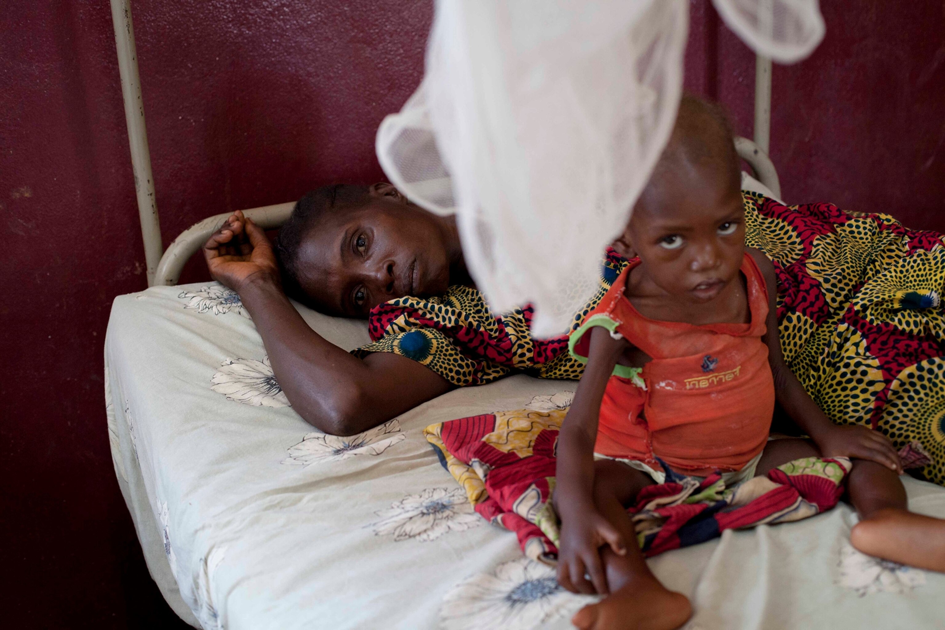 A mother and her child, who is suffering from malnutrition, share a bed at a paediatrics hospital in Bangui, Central African Republic, February 25, 2014.