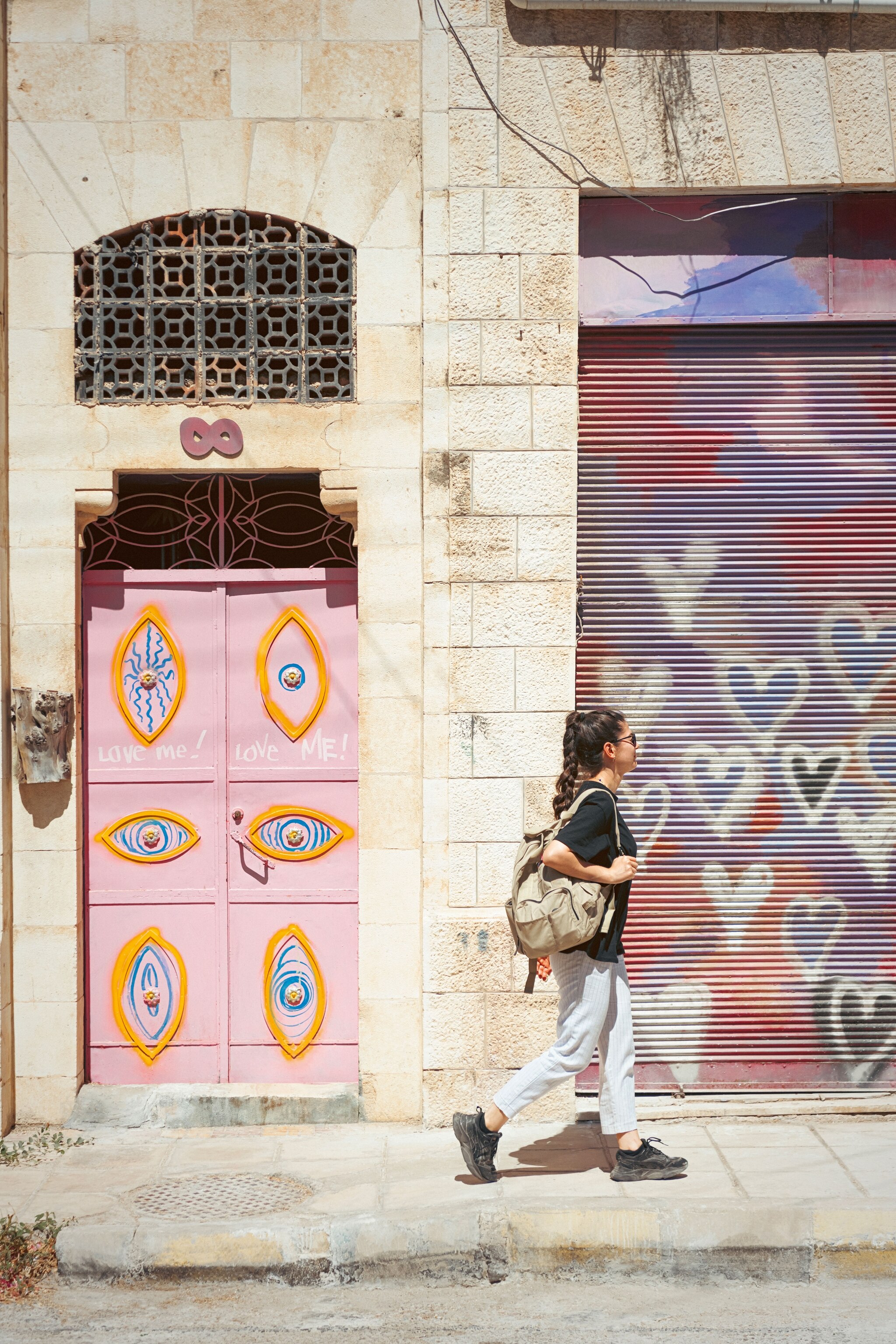 woman walking in front of colourful door - pink and purple