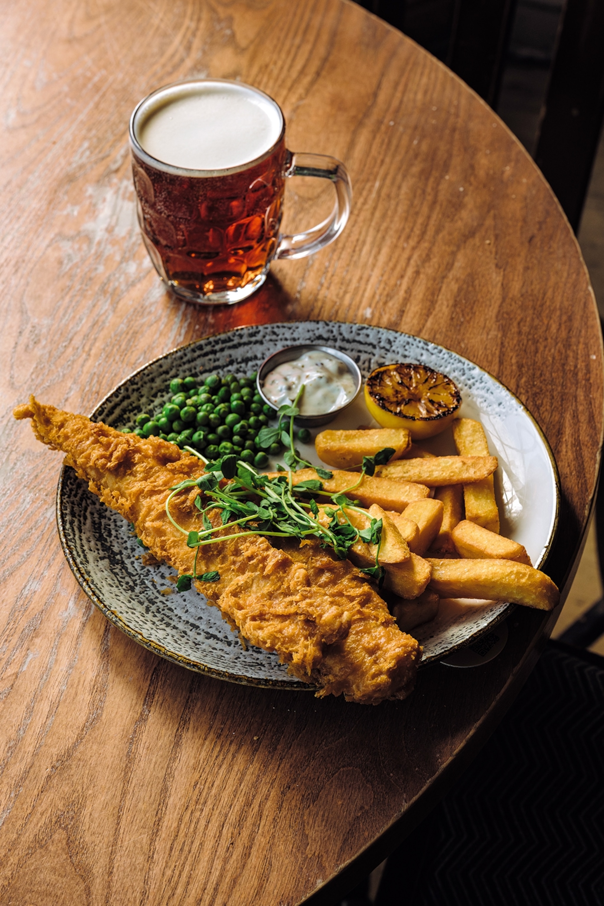 A plate of fish and chips with a pint.