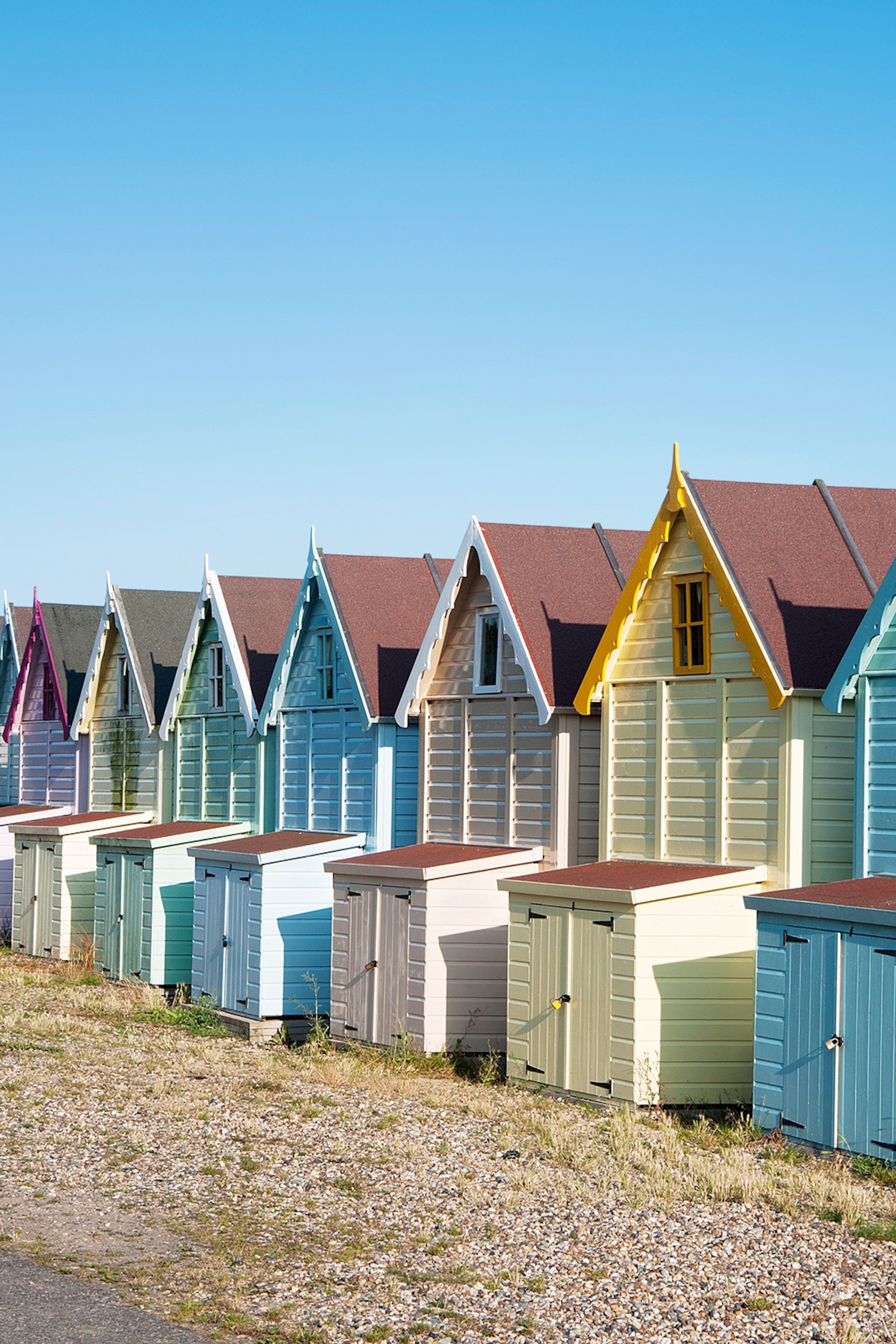 A row of wooden beach huts with peaked roofs.