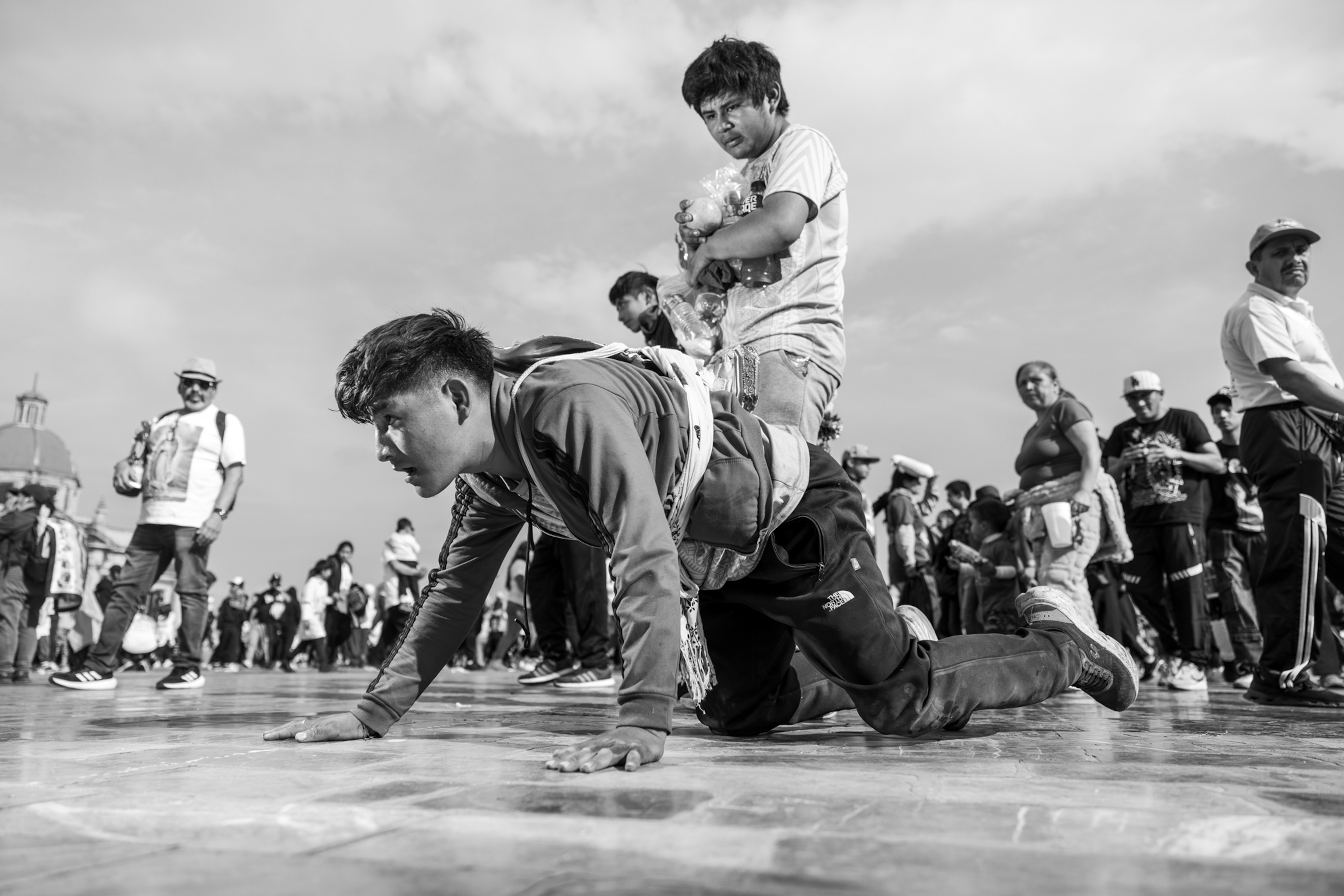 A group of people on a concrete surface. One person is crawling.