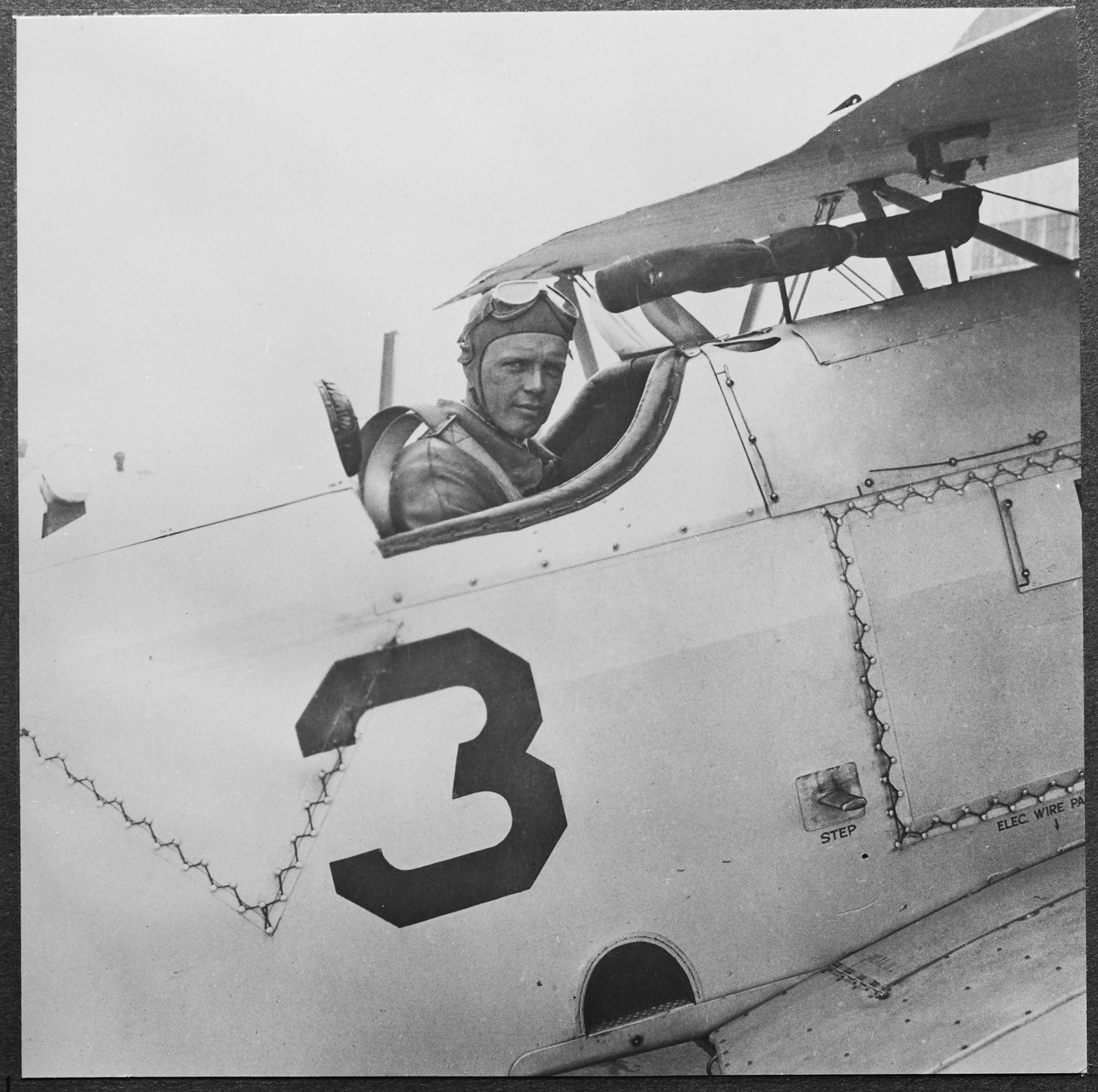 American aviator Charles Lindbergh, wearing an aviator's cap, his flying goggles raised on his head as he sits in the open cockpit of an aircraft with a large '3' on the fuselage, United States, circa 1925.